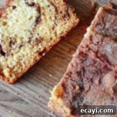 Ribboned Cinnamon Raisin Quick Loaf 7 A close up photo of a sliced loaf of cinnamon raisin swirl quick bread on a wooden cutting board.
