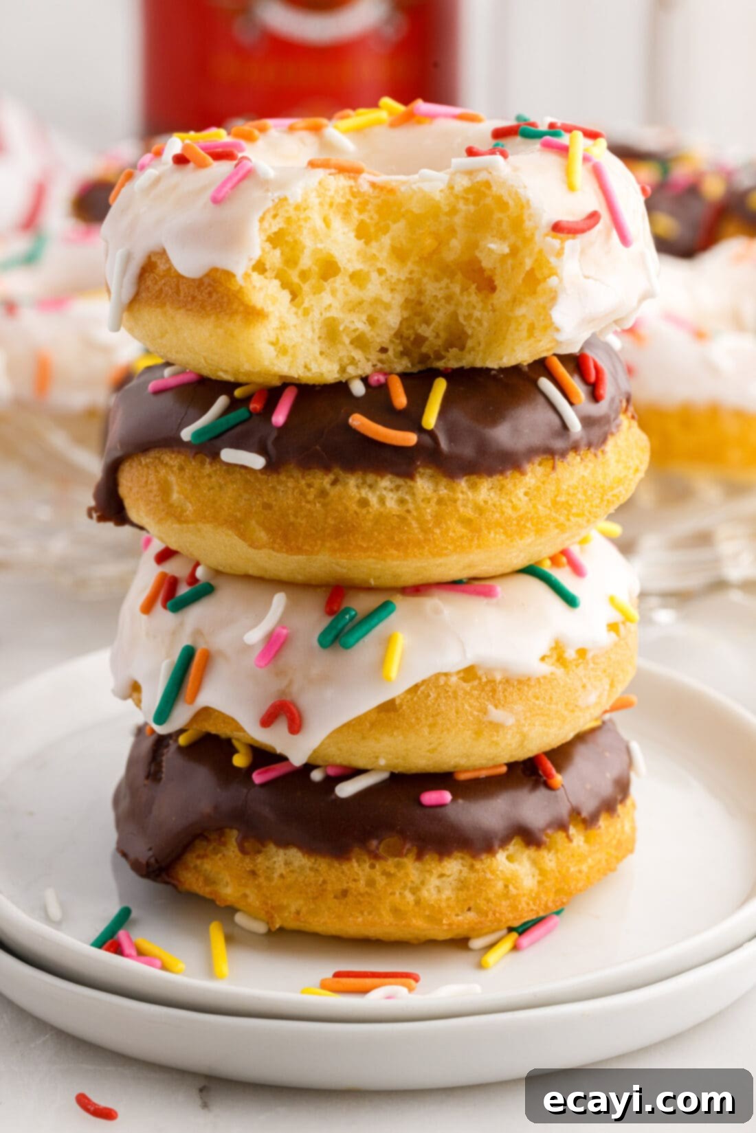 Effortless Cake Mix Donuts 2 Cake Mix Donut with a bite taken out sitting on top of a stack of three Cake Mix Donuts