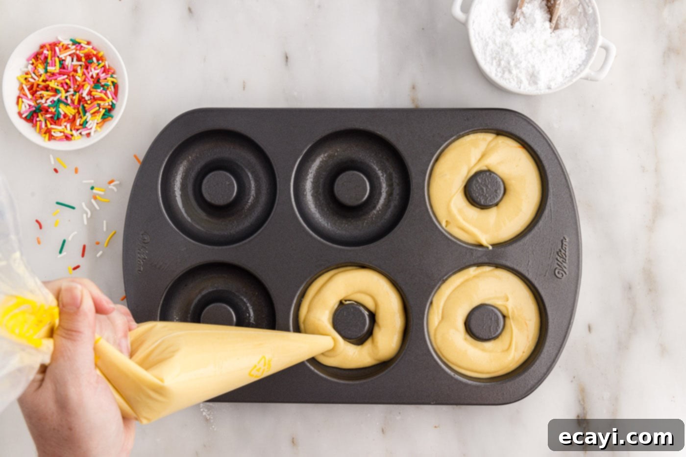 Effortless Cake Mix Donuts 7 piping cake mix donut batter into a donut pan