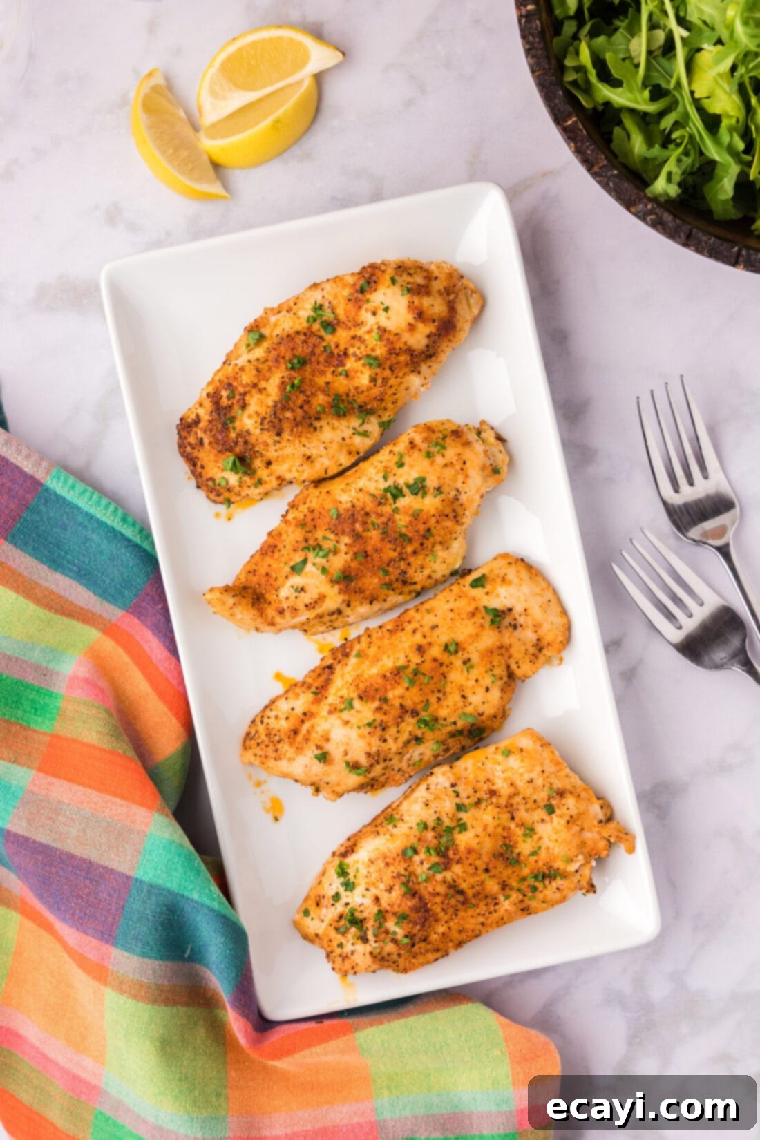 Cajun Spiced Blackened Chicken 3 Two pieces of Blackened Chicken served on a white platter, garnished with fresh herbs and lemon wedges.