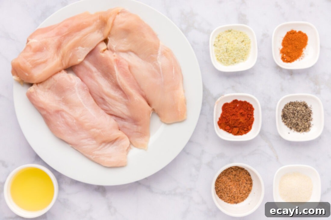 Cajun Spiced Blackened Chicken 4 A collection of spices, olive oil, and raw chicken breasts laid out on a cutting board, ready for making blackened chicken.