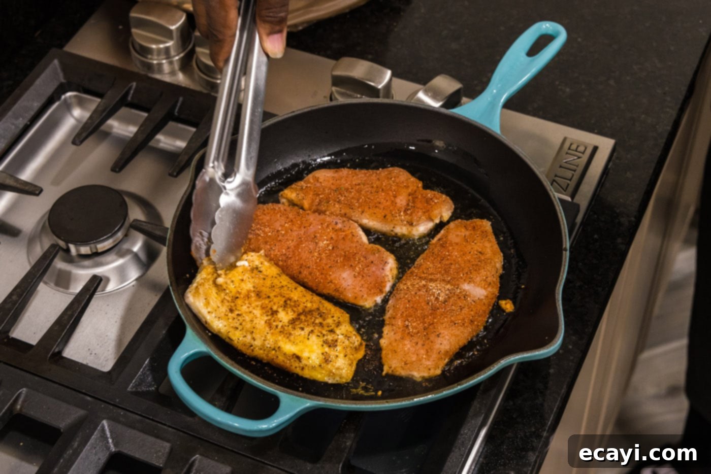Cajun Spiced Blackened Chicken 9 Tongs flipping seared chicken breasts in a skillet, revealing their rich, dark crust.