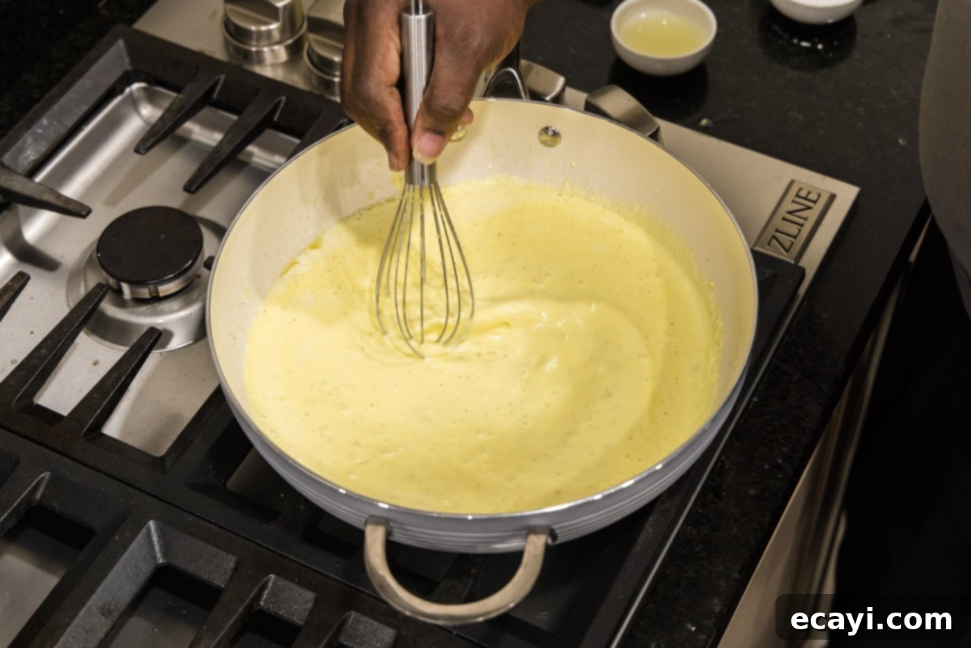 Velvet Lobster Delight 12 Continuously whisking the egg mixture into the cream sauce to temper it correctly.