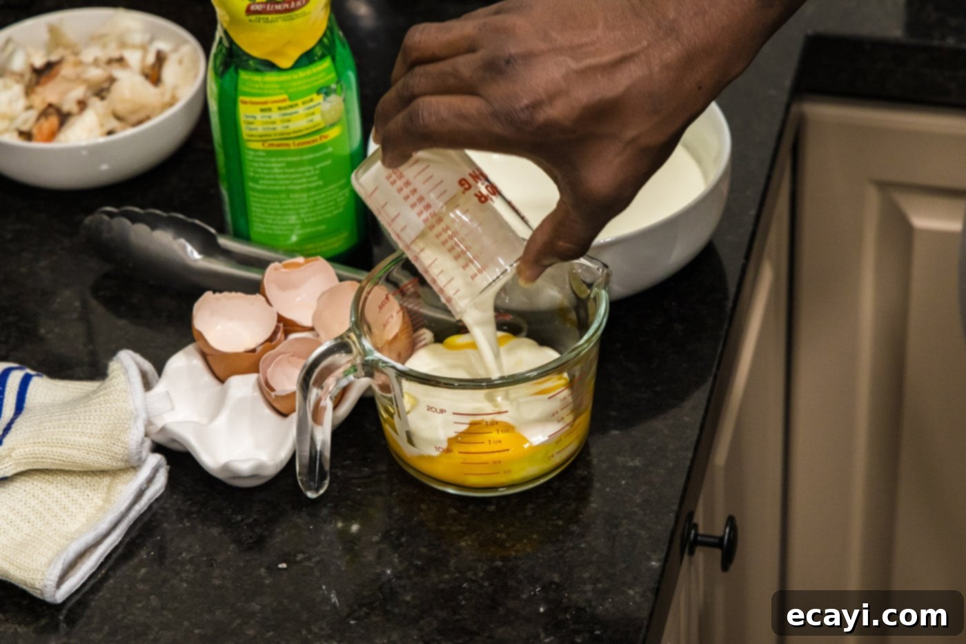 Velvet Lobster Delight 5 Pouring heavy cream into a measuring cup with egg yolks, then whisking the mixture.