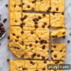 Easy Cake Mix Cookie Bars 14 Close-up of baked Cake Mix Cookie Bars on parchment paper, speckled with melted chocolate chips, ready to be cut.