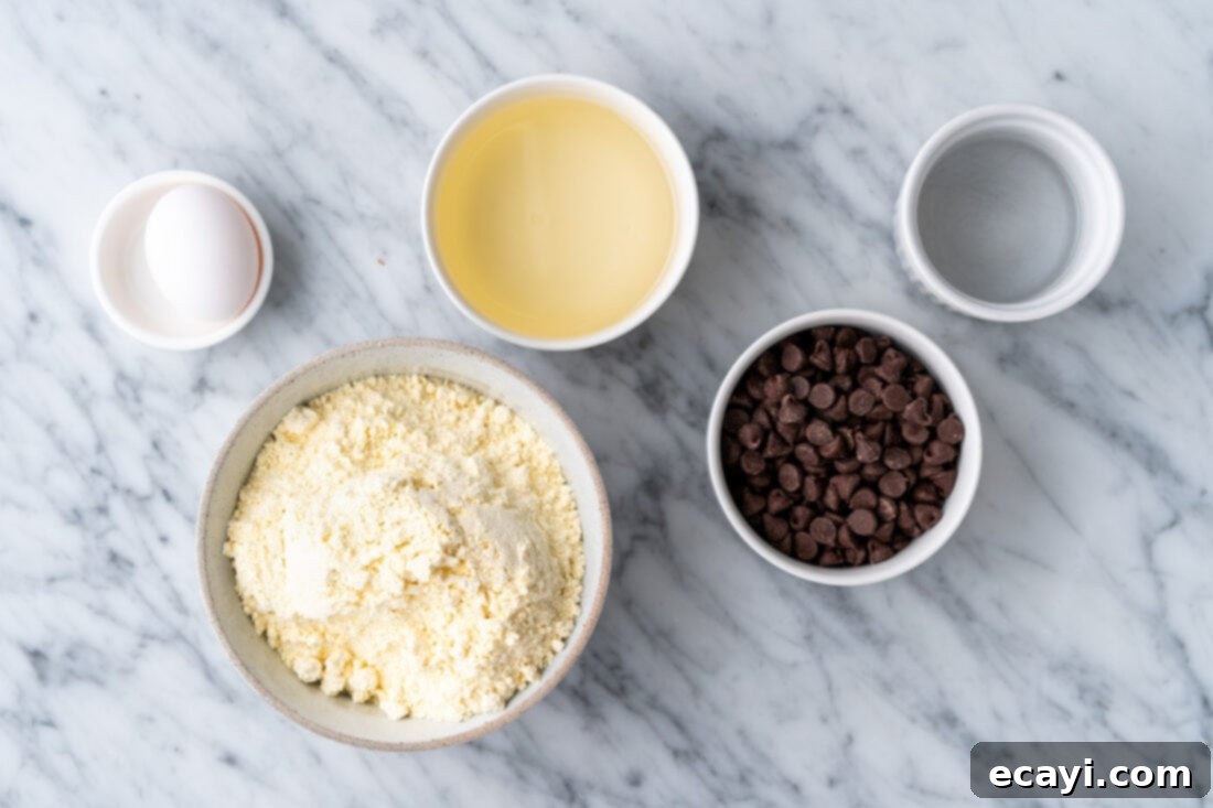 Easy Cake Mix Cookie Bars 4 The five simple ingredients laid out for Cake Mix Cookie Bars: a yellow cake mix box, a bowl of chocolate chips, vegetable oil, eggs, and a glass of water.