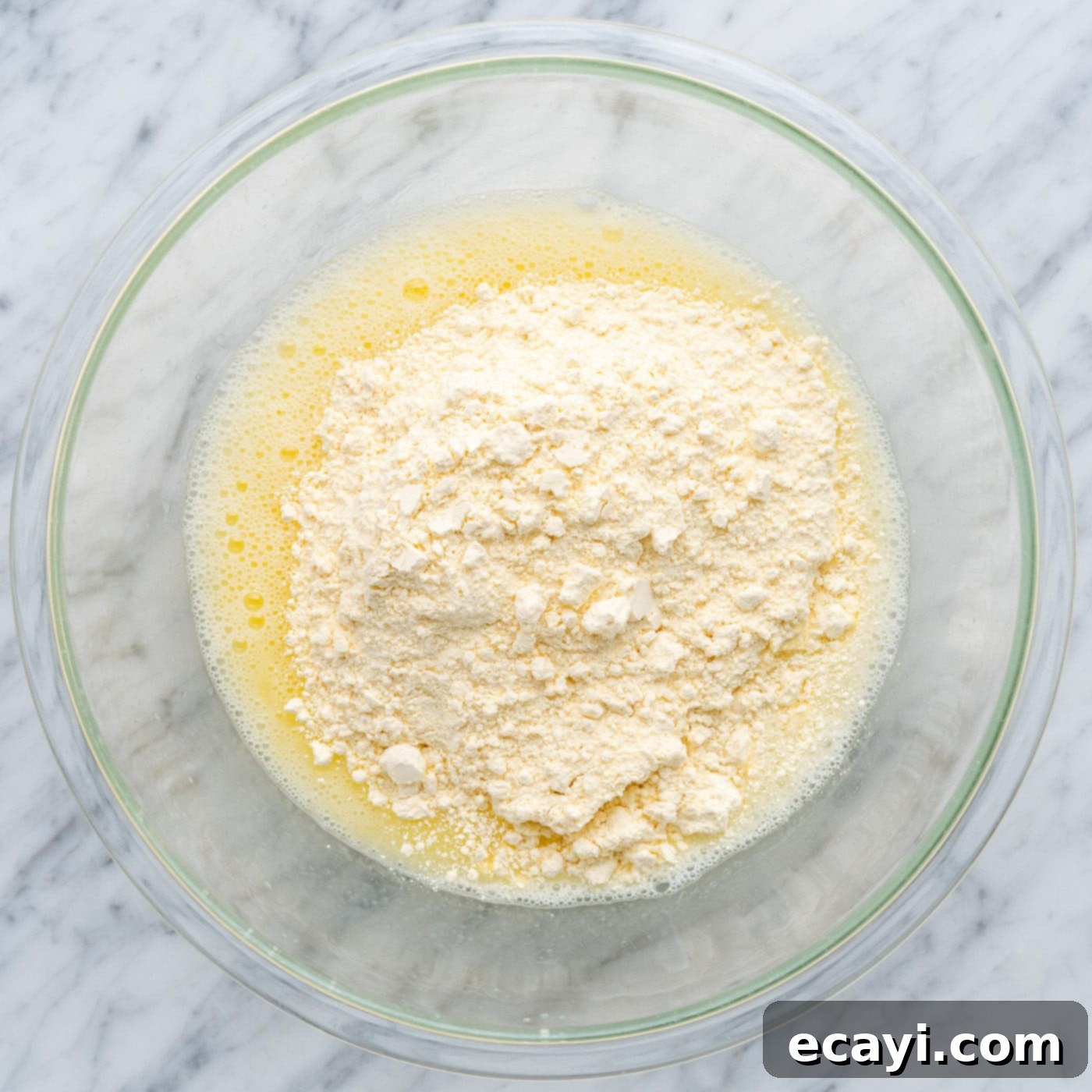 Easy Cake Mix Cookie Bars 6 Dry yellow cake mix being poured into a bowl with whisked wet ingredients, ready to be combined for the cookie bar batter.