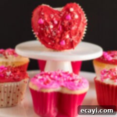 Heartfelt Valentine Cupcakes 12 Valentine Heart Cupcake on a cupcake stand with more cupcakes around it, showcasing a delightful dessert display.