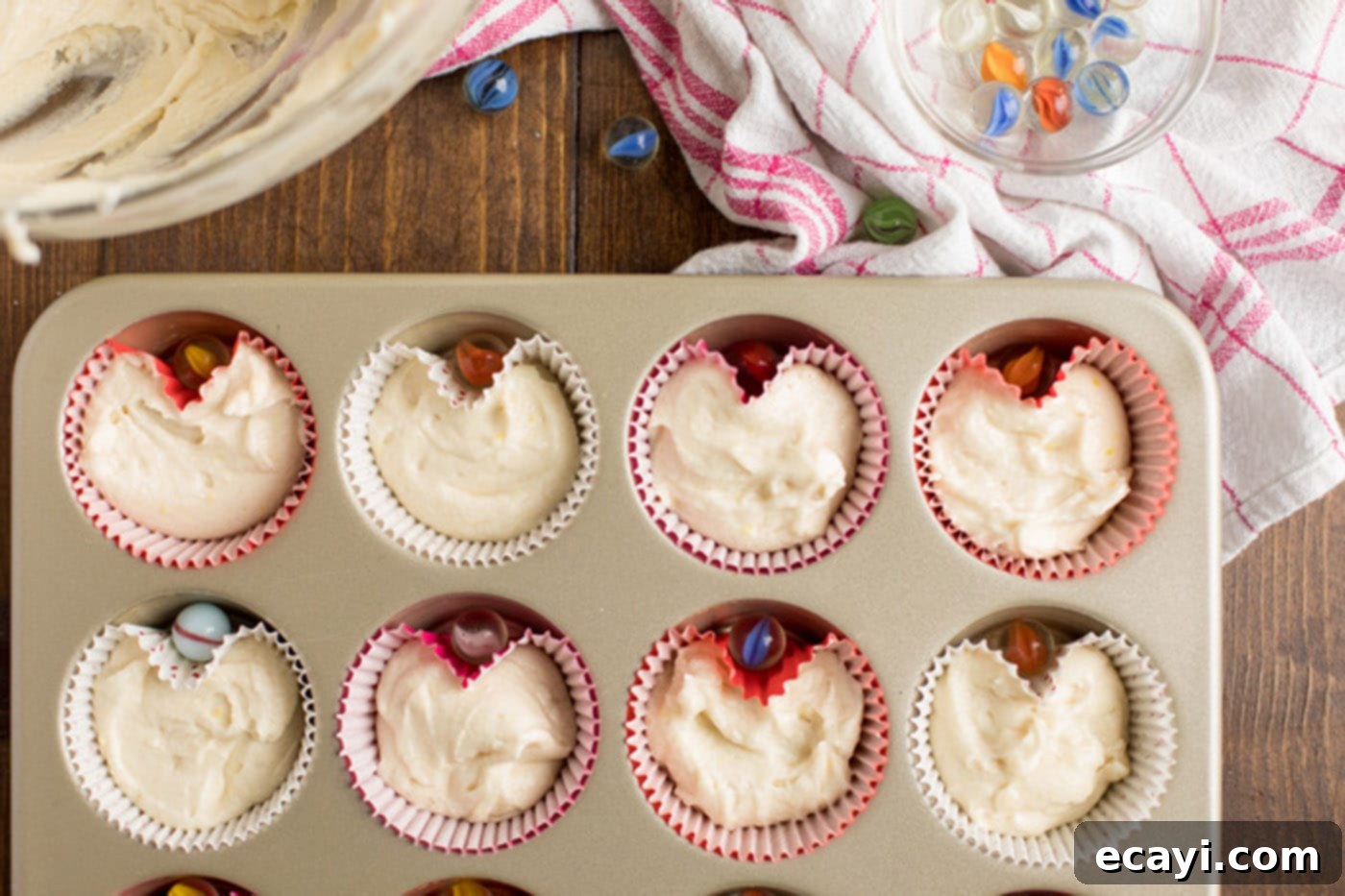 Heartfelt Valentine Cupcakes 8 Cupcake batter in liners in a muffin pan with marbles strategically placed to create heart shapes.