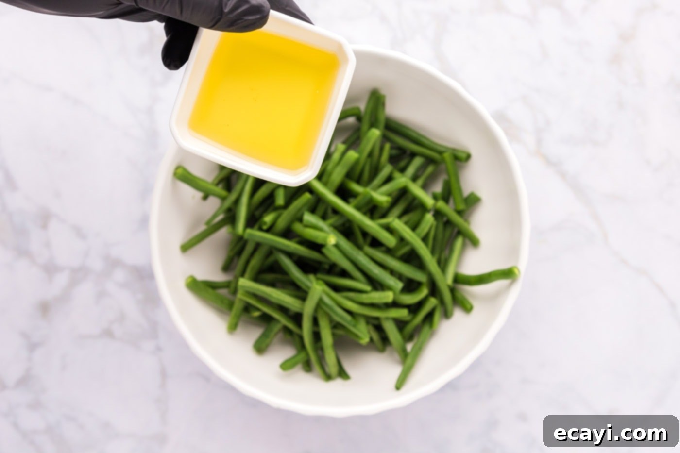 Crispy Roasted Green Beans 5 adding olive oil to green beans in a bowl