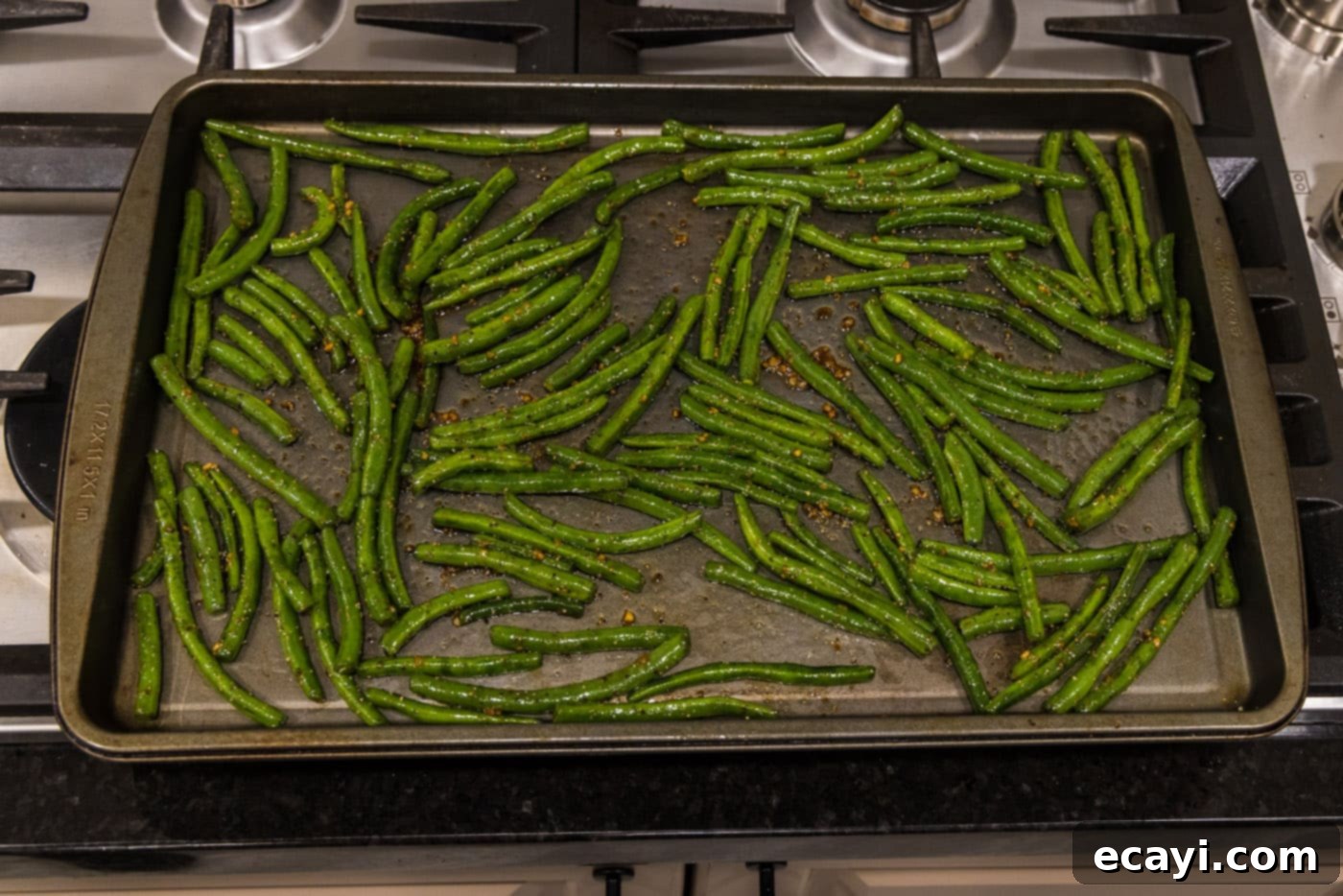 Crispy Roasted Green Beans 9 green beans spread out in a single layer on a large baking sheet for roasting