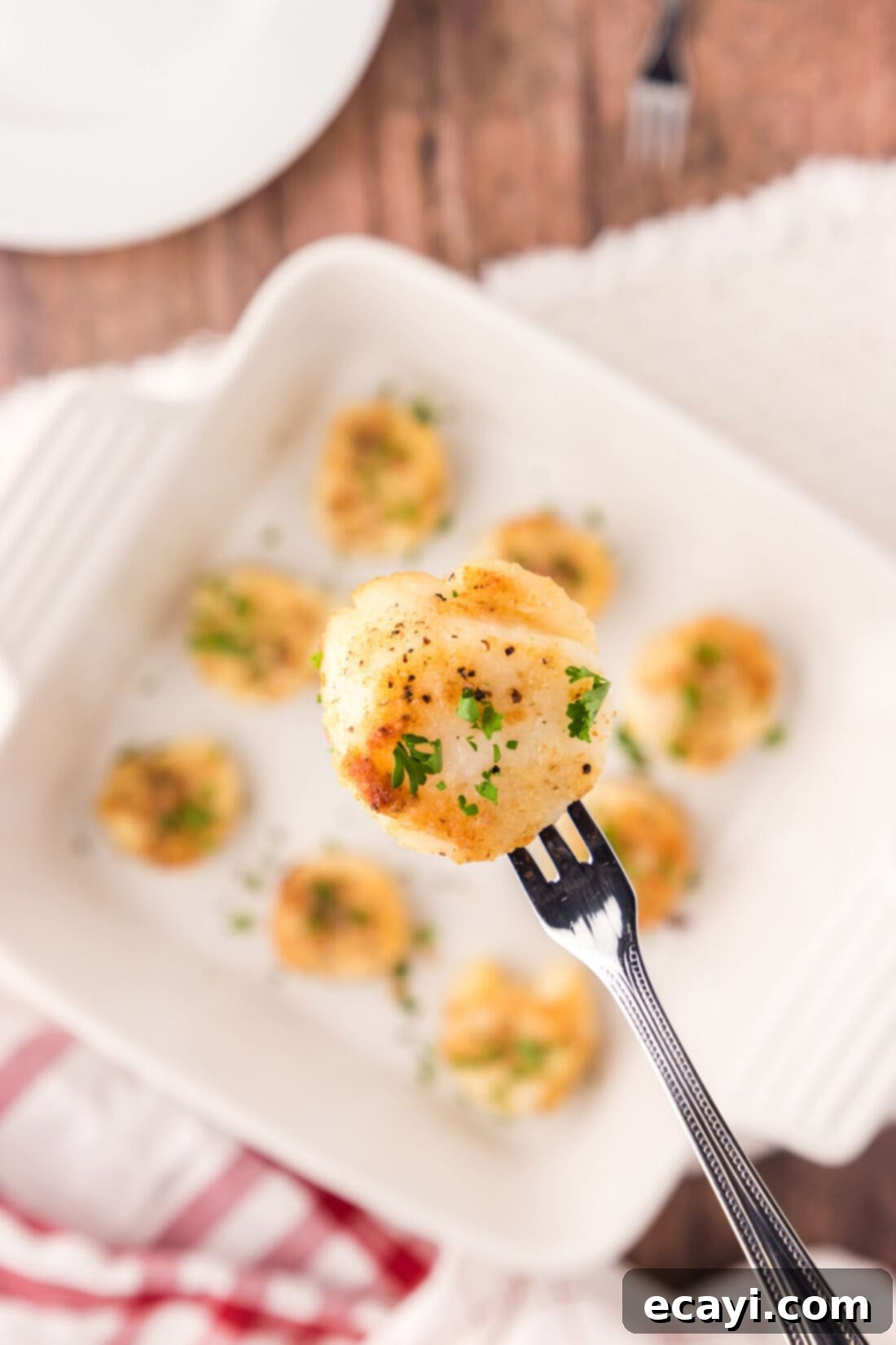 Golden Baked Scallops 2 Close up of a golden-crusted Baked Scallop on a seafood fork, showing the crispy topping and tender interior.