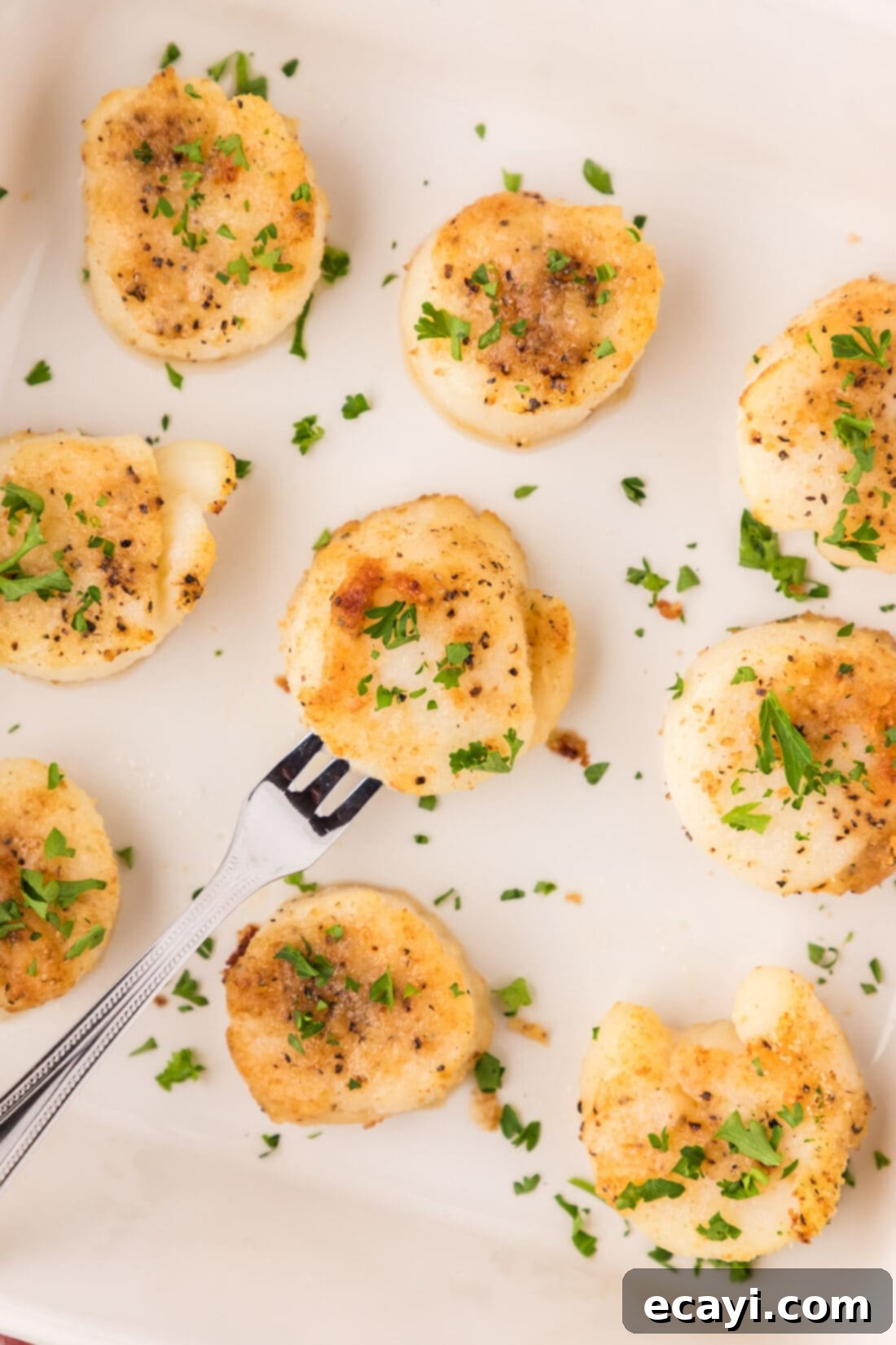 Golden Baked Scallops 11 Close up of perfectly Baked Scallops arranged in a serving dish, with a seafood fork nearby.