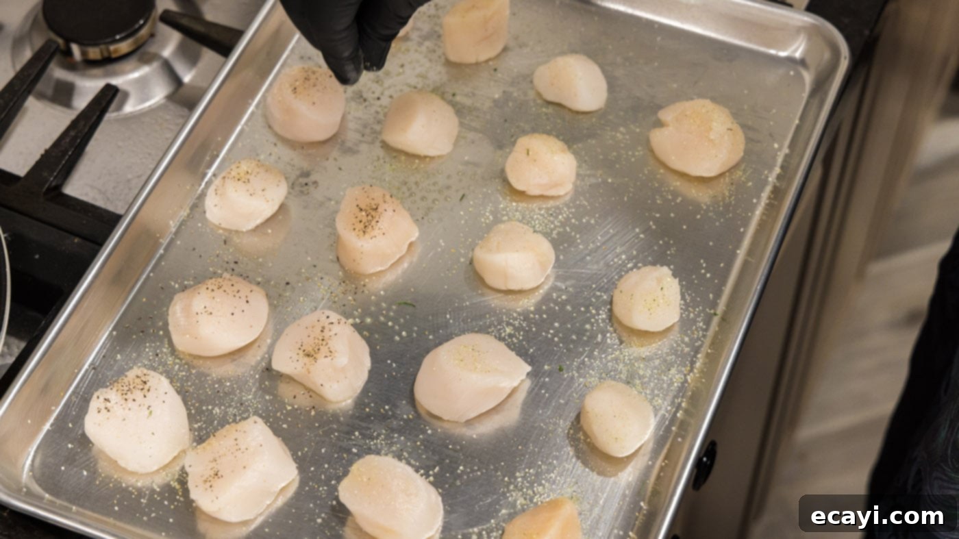Golden Baked Scallops 6 A hand sprinkling garlic salt and pepper onto scallops on a baking sheet.