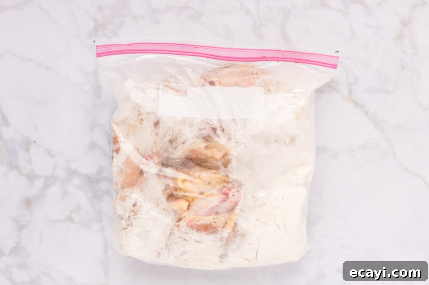 Crispy Fried Chicken Wings 6 chicken wings in a large zip top bag with flour, being shaken to coat.