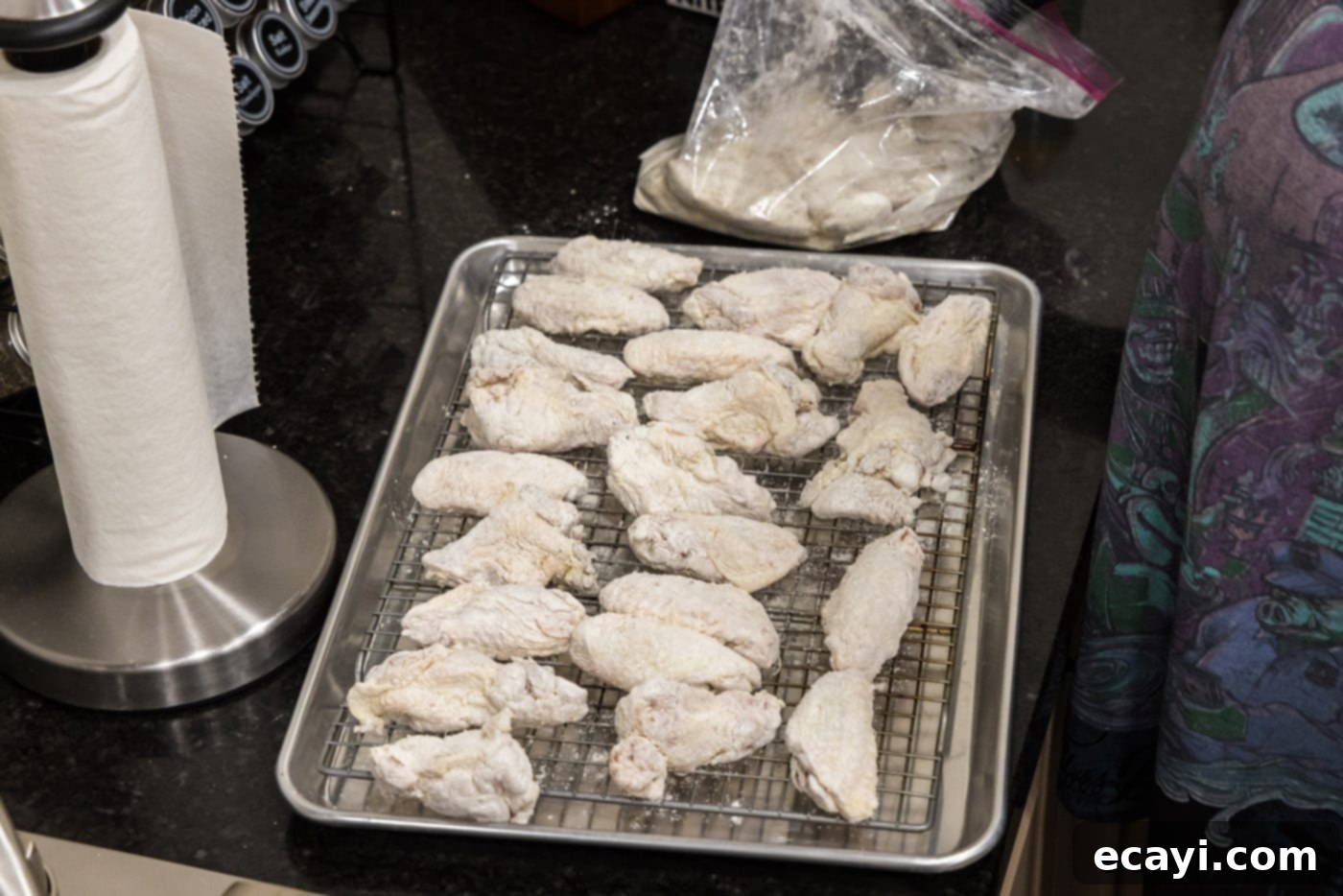 Crispy Fried Chicken Wings 7 floured chicken wings resting on a baking sheet with a wire rack.