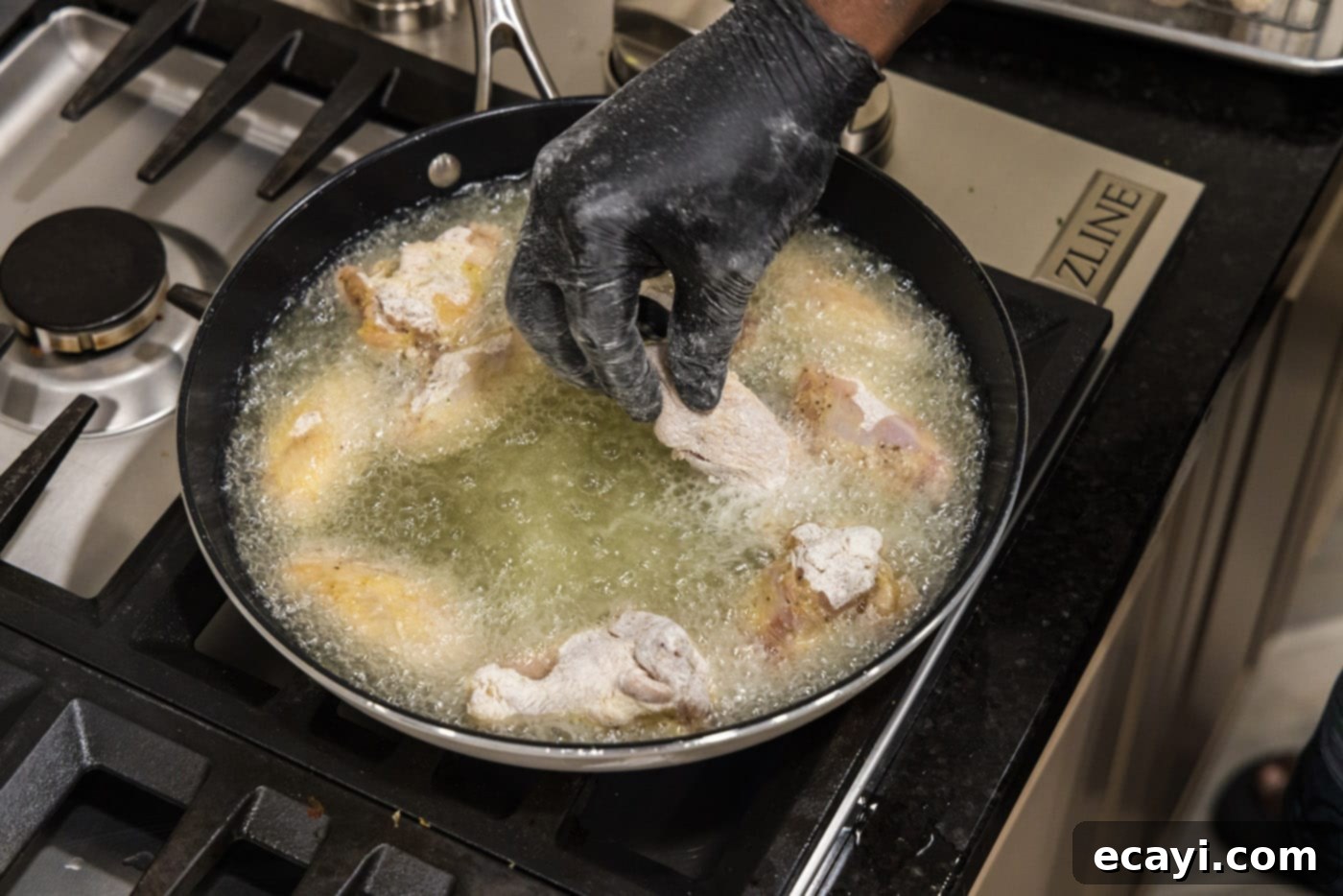 Crispy Fried Chicken Wings 8 adding chicken wings to hot oil in a skillet, showing careful placement.
