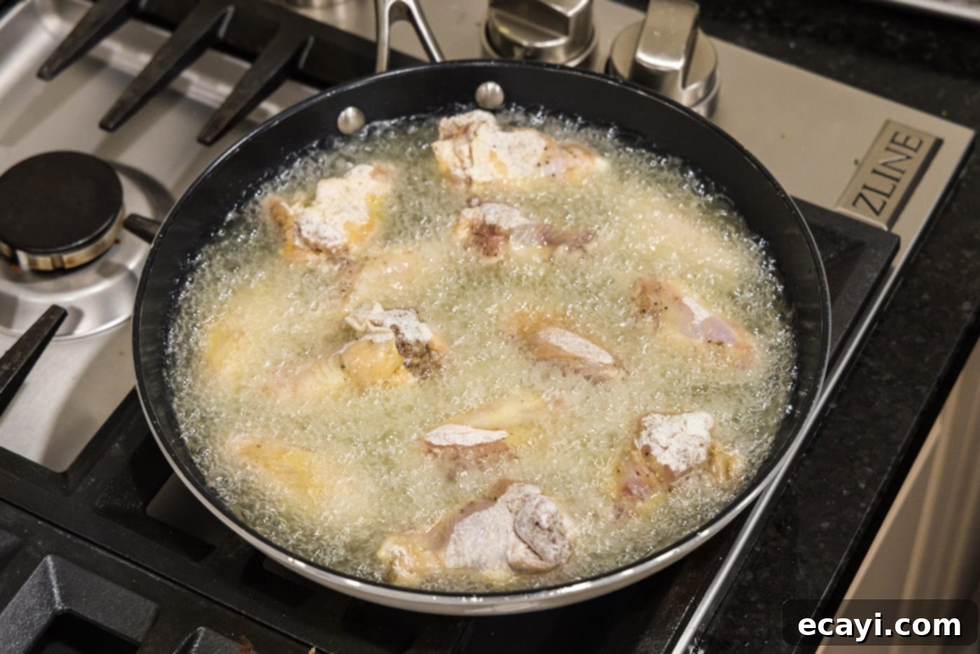 Crispy Fried Chicken Wings 9 frying chicken wings sizzling in a skillet of hot oil.