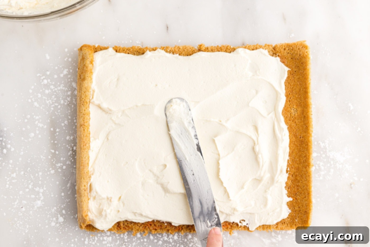Swirled Carrot Delight 17 Spreading smooth cream cheese filling evenly over the unrolled carrot cake.
