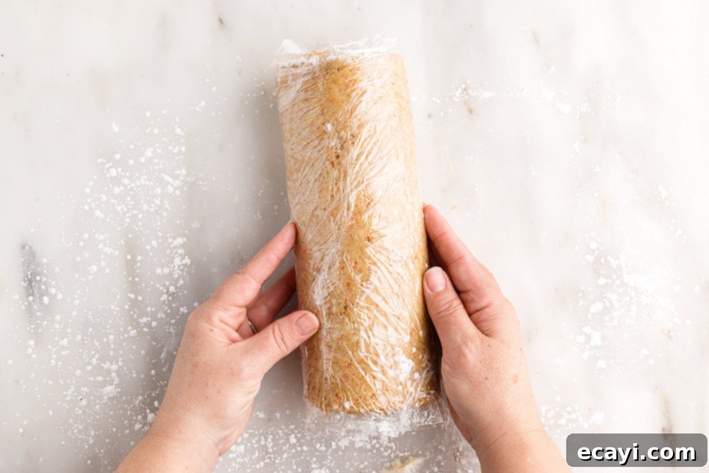 Swirled Carrot Delight 19 Carrot cake roll securely wrapped in plastic wrap, ready for chilling to set its shape.