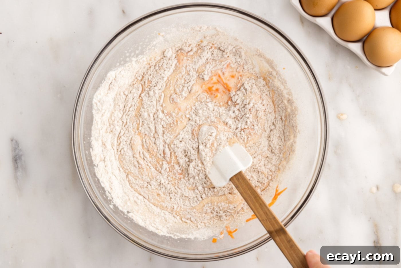Swirled Carrot Delight 7 Folding dry ingredients into wet ingredients for carrot cake batter with a rubber spatula.