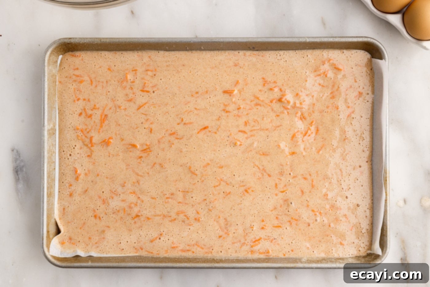Swirled Carrot Delight 9 Carrot cake roll batter evenly spread in a parchment-lined jelly roll pan.