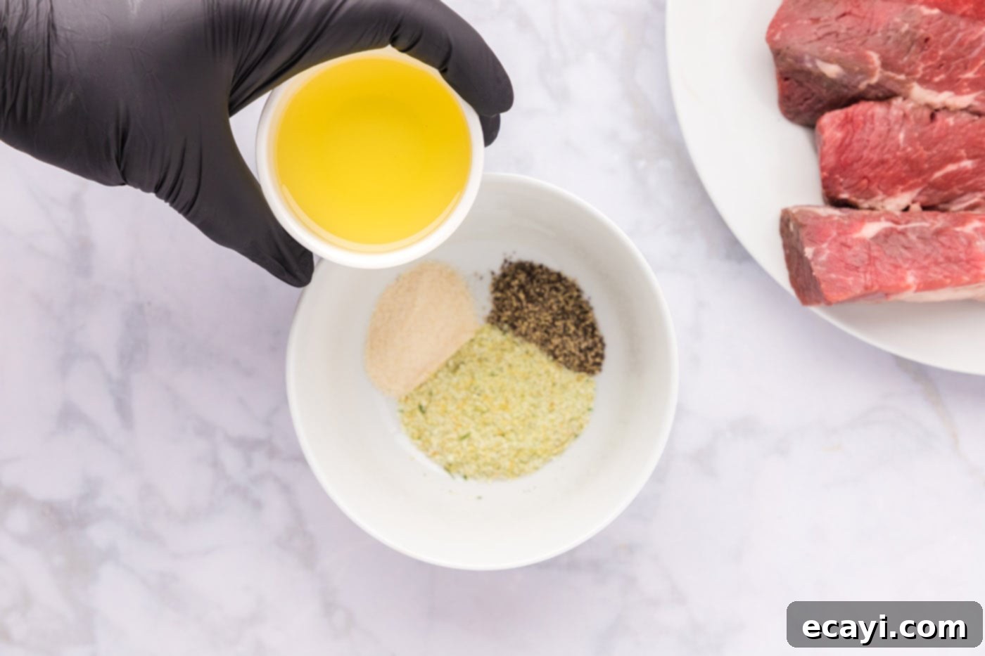 Tender Boneless Beef Short Ribs 5 Adding olive oil to a bowl of seasoned boneless beef short ribs, preparing them for searing.