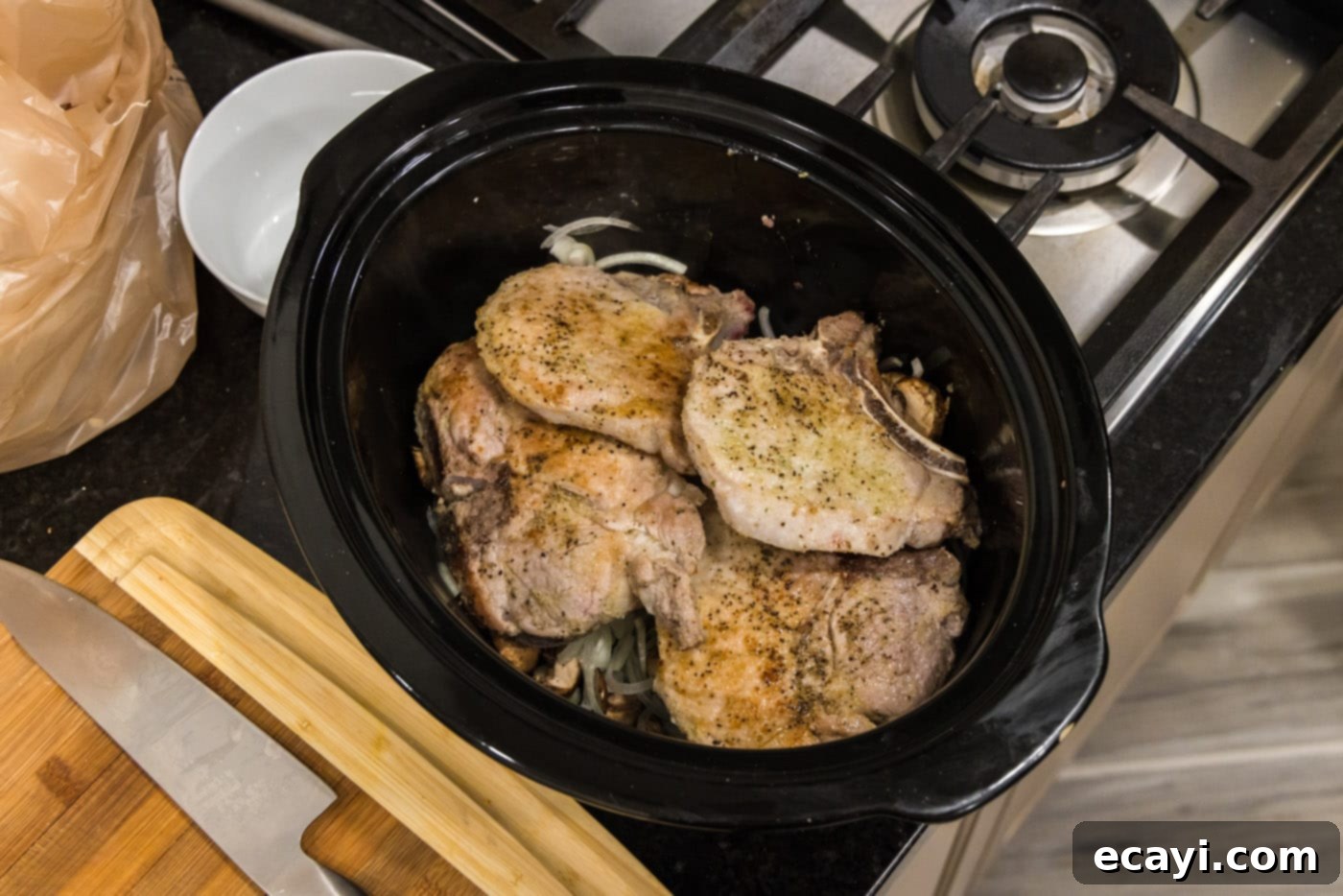 Fall-Off-The-Bone Pork Chops 11 Seared pork chops arranged over mushrooms and onions in the slow cooker