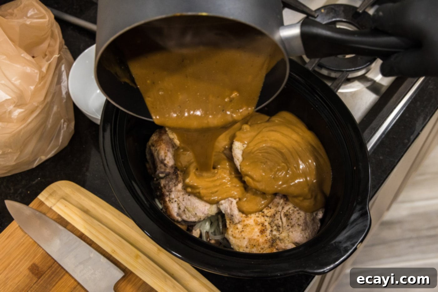 Fall-Off-The-Bone Pork Chops 12 Pouring rich brown gravy over pork chops, mushrooms, and onions in the crockpot