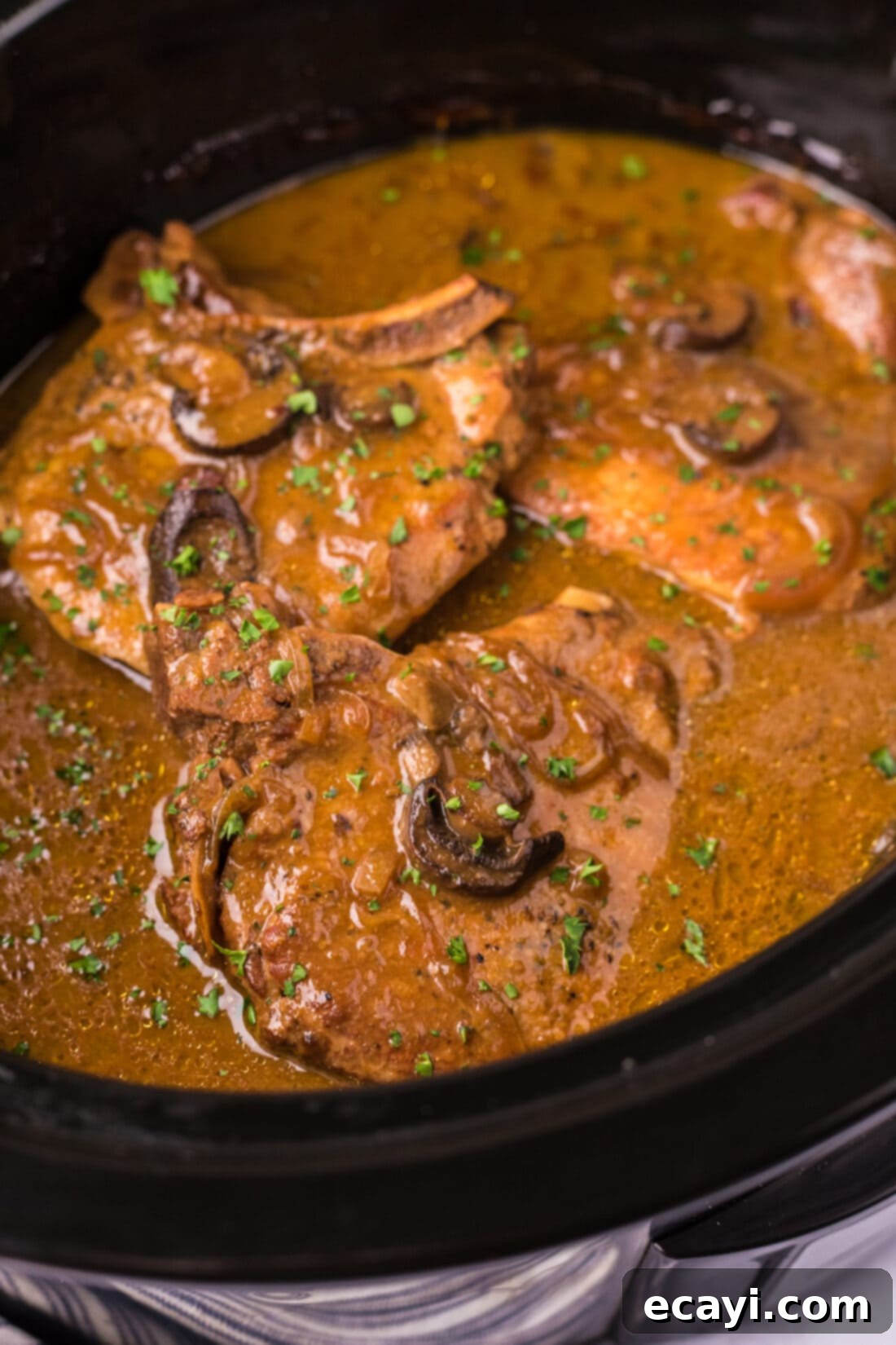 Fall-Off-The-Bone Pork Chops 14 Close up photo of Crockpot Pork Chops in a crockpot, showing the rich gravy and tender meat