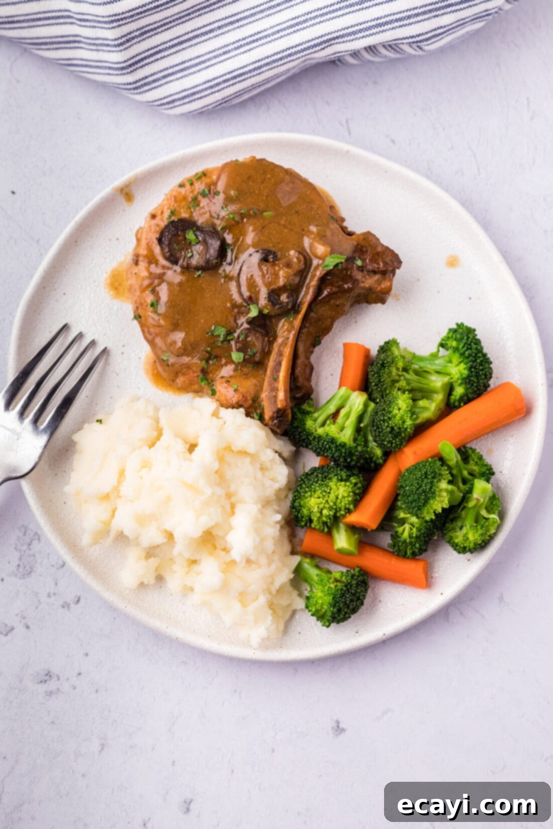Fall-Off-The-Bone Pork Chops 3 Crockpot Pork Chop served on a plate with mashed potatoes and mixed vegetables