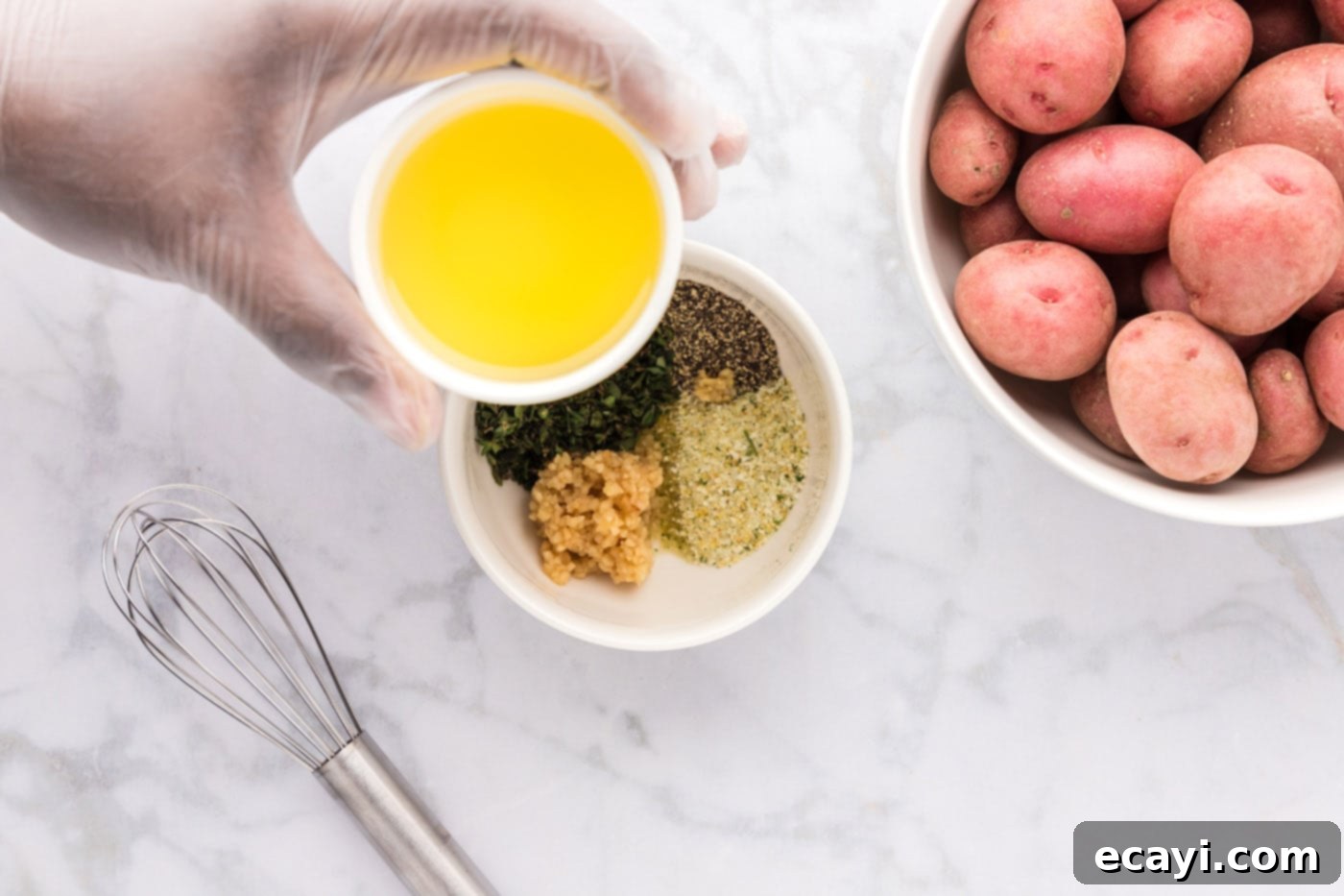 Crispy Roasted Red Potato Medley 6 olive oil being poured over a bowl of seasonings