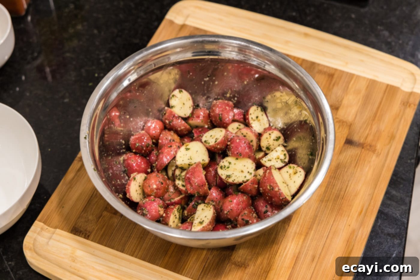Crispy Roasted Red Potato Medley 8 baby red potatoes in a bowl, being tossed with olive oil and seasoning until completely covered