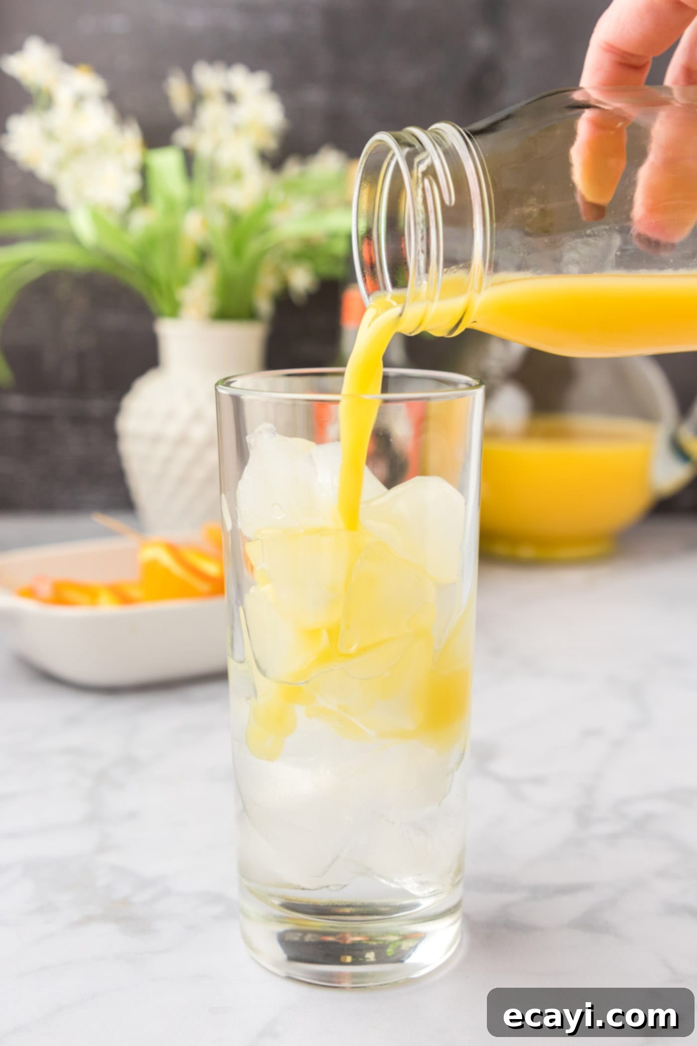 Golden Peach Nectar 6 pouring orange juice into glass of peach schnapps and ice