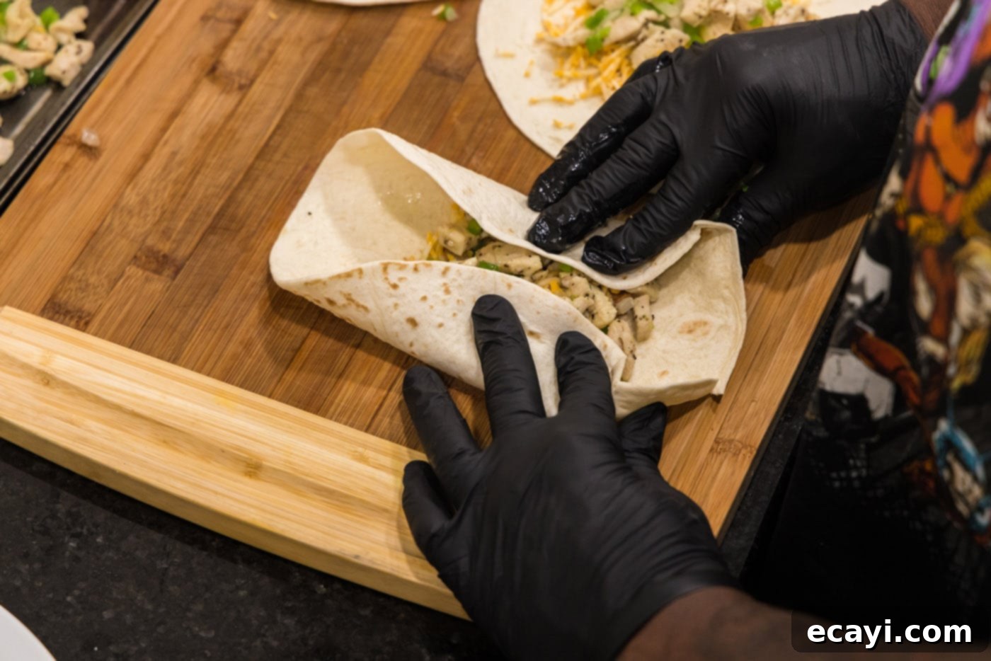 Chimichanga Perfection 14 Hands demonstrating the initial fold of a chimichanga tortilla, bringing the sides inward over the filling