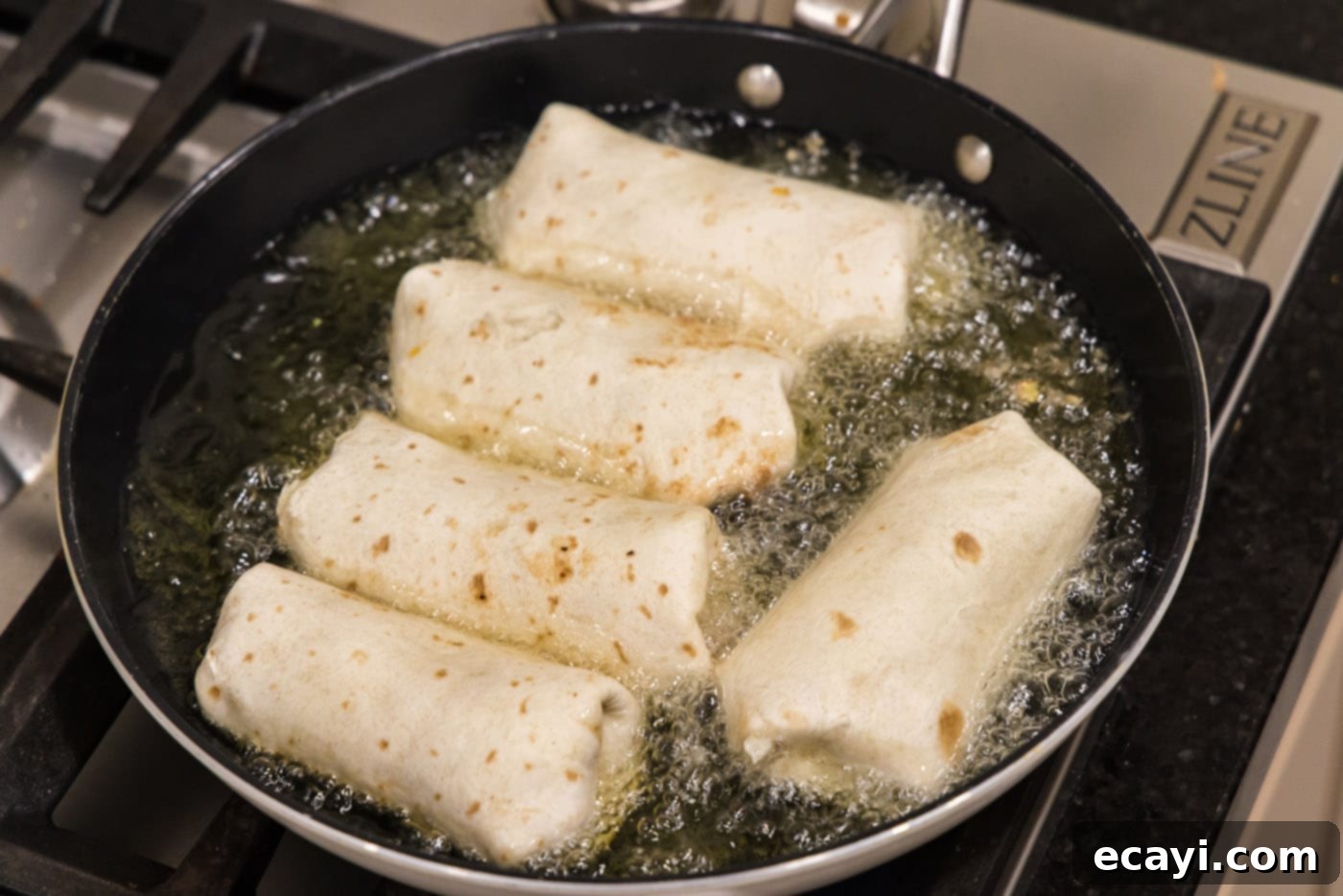Chimichanga Perfection 18 Chicken chimichangas deep-frying in hot vegetable oil in a large skillet until golden brown and crispy