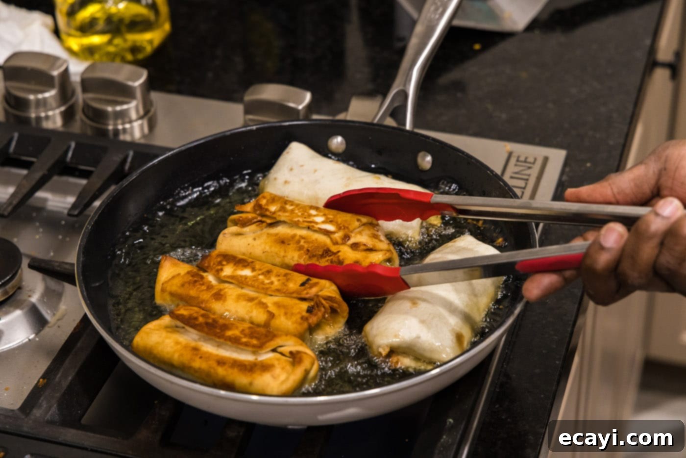 Chimichanga Perfection 19 Tongs carefully flipping deep-frying chimichangas in oil to ensure even browning on all sides