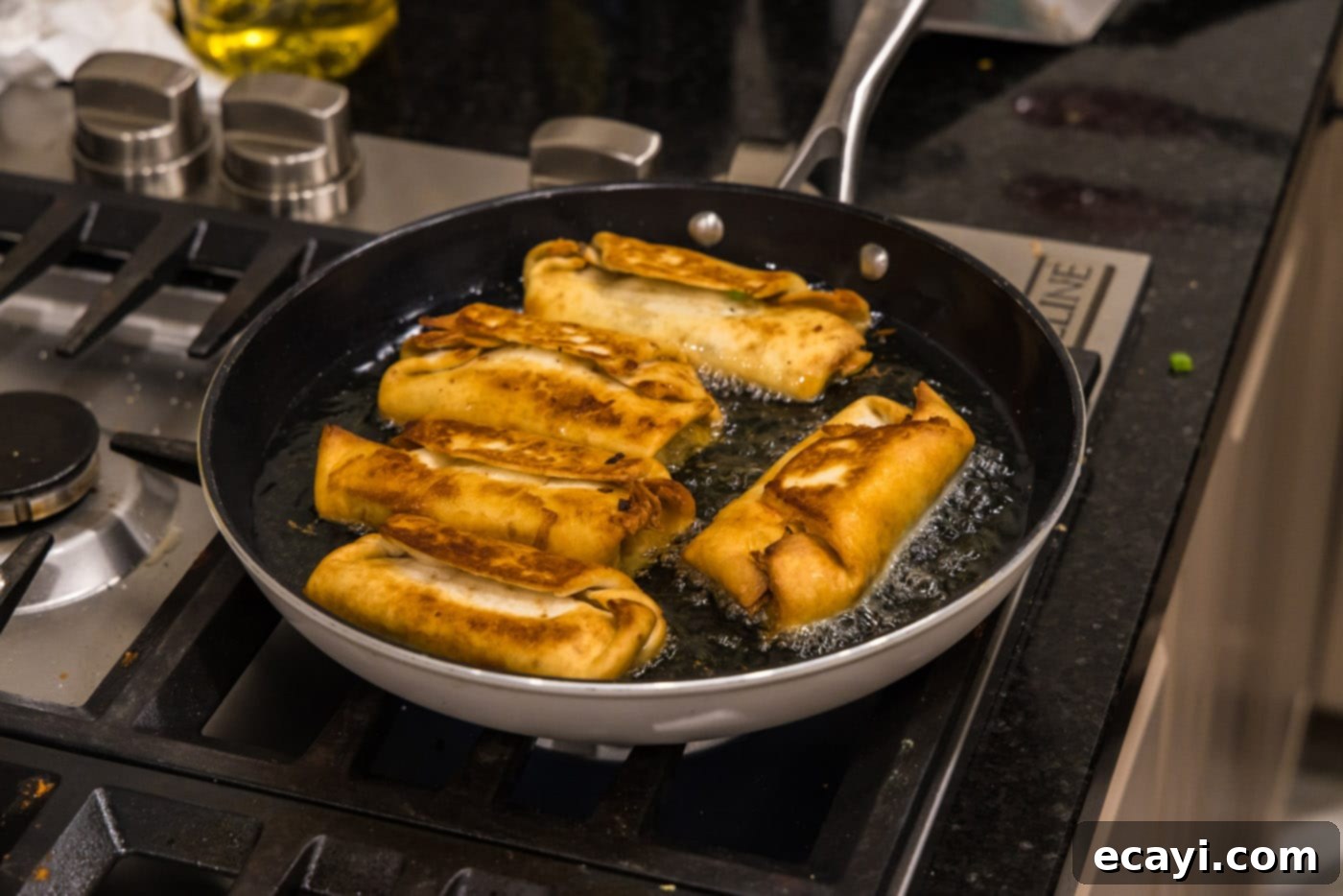 Chimichanga Perfection 20 Freshly deep-fried chimichangas cooling on the stovetop after being removed from the hot oil