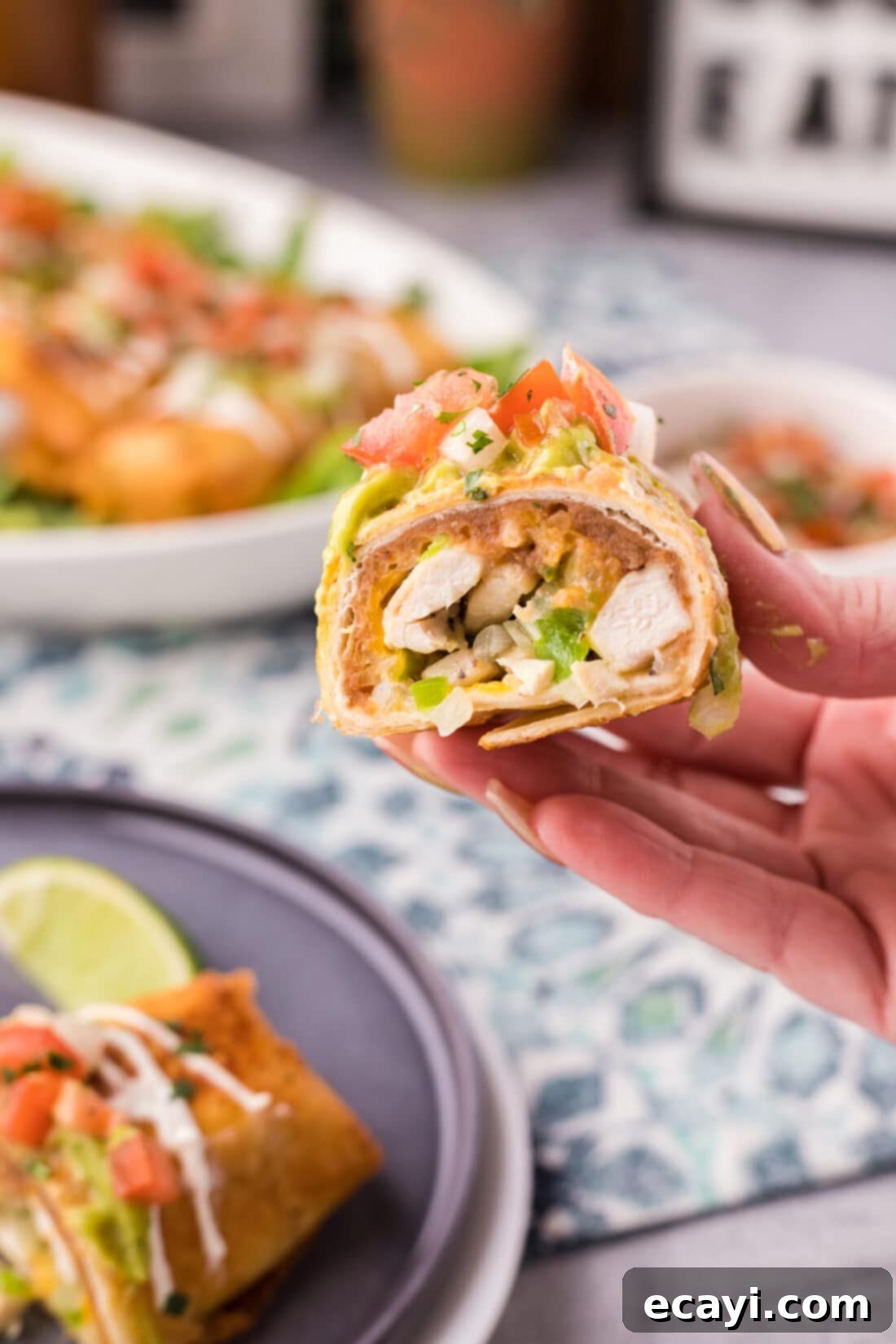 Chimichanga Perfection 21 Hand holding a perfectly deep-fried chicken chimichanga cut in half, revealing the flavorful chicken, bean, and cheese filling