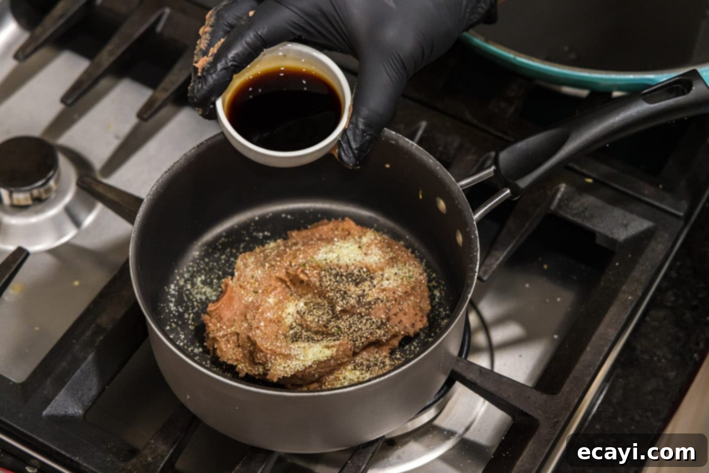 Chimichanga Perfection 6 Soy sauce being added to refried beans in a saucepan with seasonings for chimichanga filling