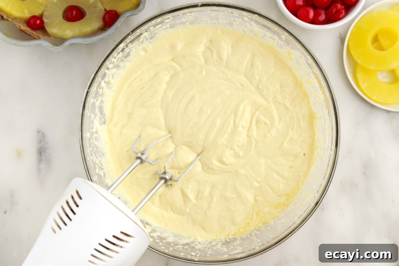 Golden Pineapple Crown Bundt Cake 11 bundt cake batter in a bowl with a mixer
