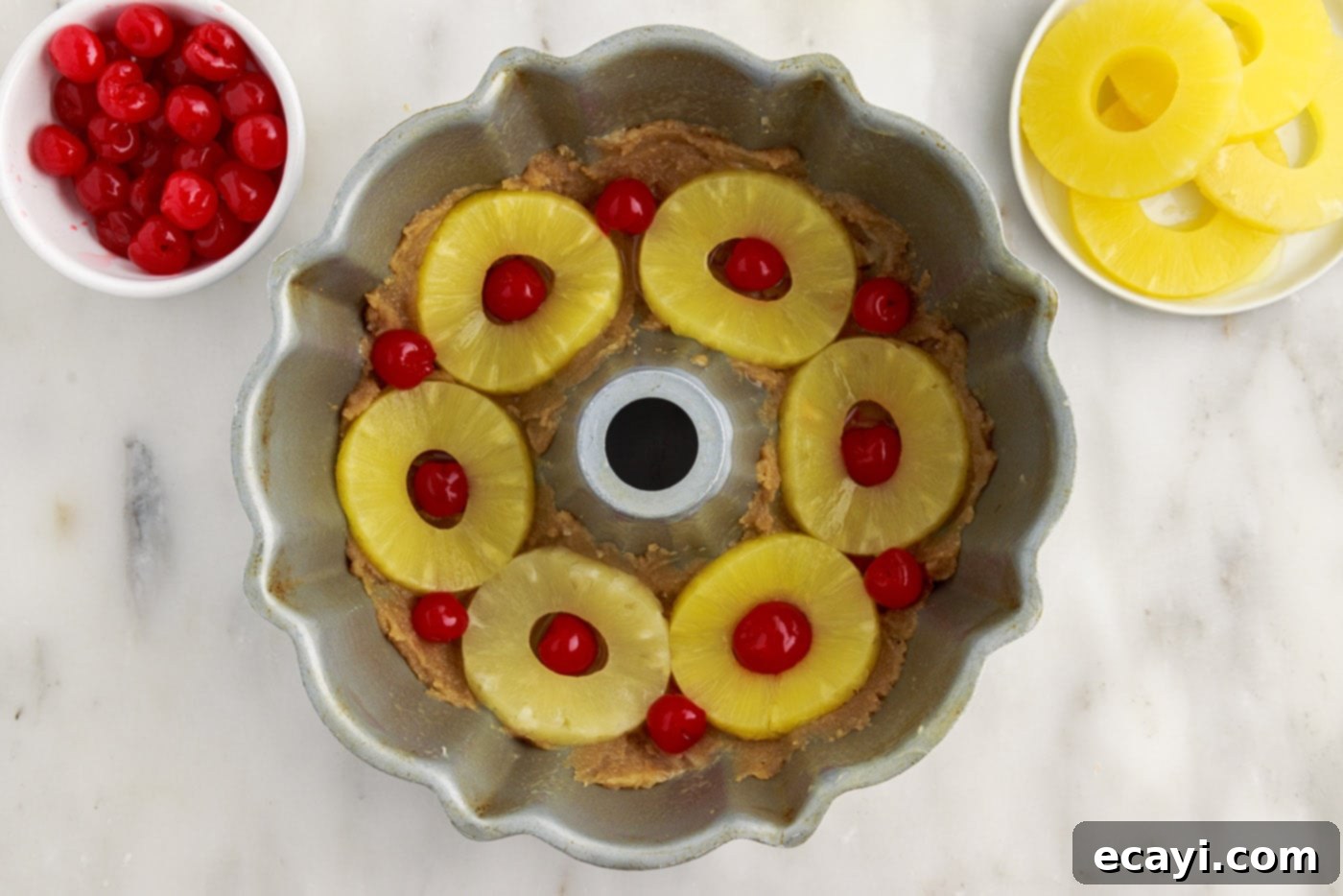 Golden Pineapple Crown Bundt Cake 9 maraschino cherries added on top of pineapple rings in a bundt pan
