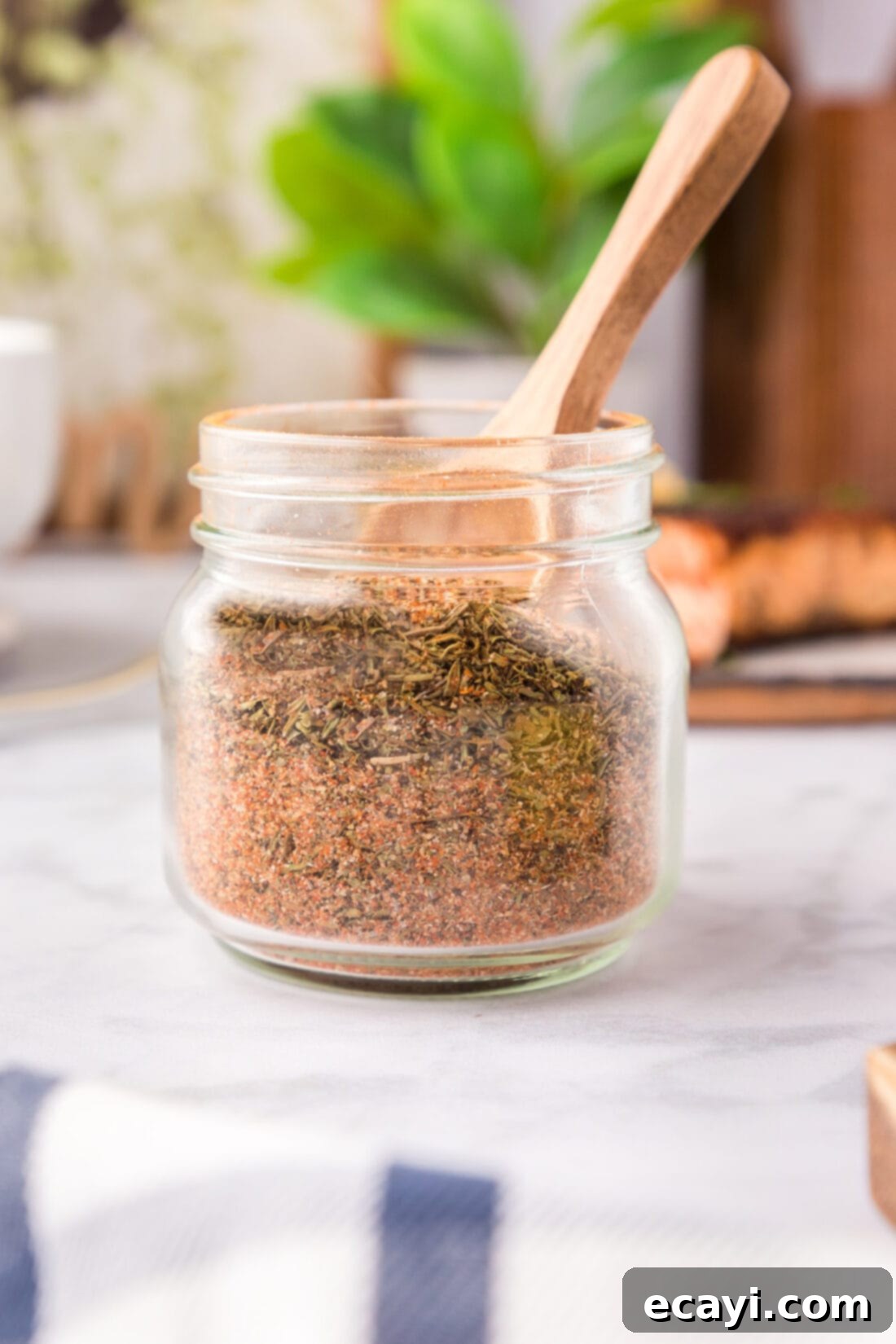 Spicy Louisiana Blend 3 A glass jar filled with homemade Cajun seasoning, with a small wooden spoon resting inside, ready for use.