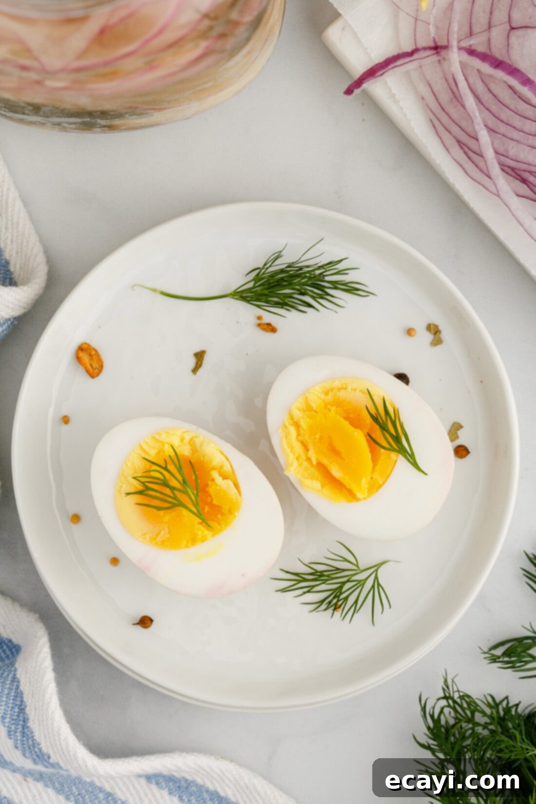 Perfectly Pickled Eggs 2 A Pickled Egg cut in half on a plate, showcasing its vibrant yolk and the translucent white, garnished with fresh dill.