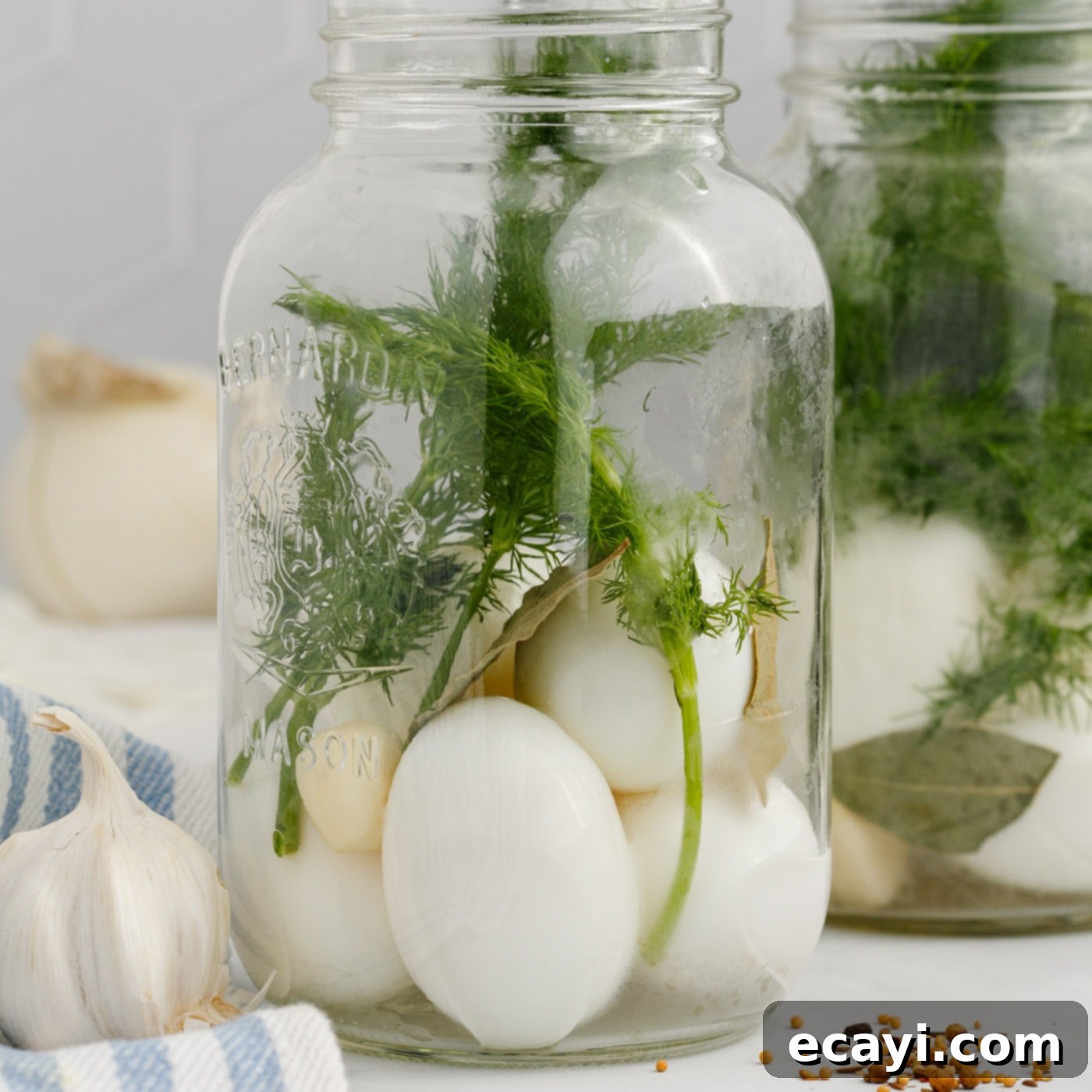 Perfectly Pickled Eggs 5 Peeled hard-boiled eggs, fresh dill, a whole garlic clove, and bay leaves neatly arranged in a mason jar, ready for the brine.