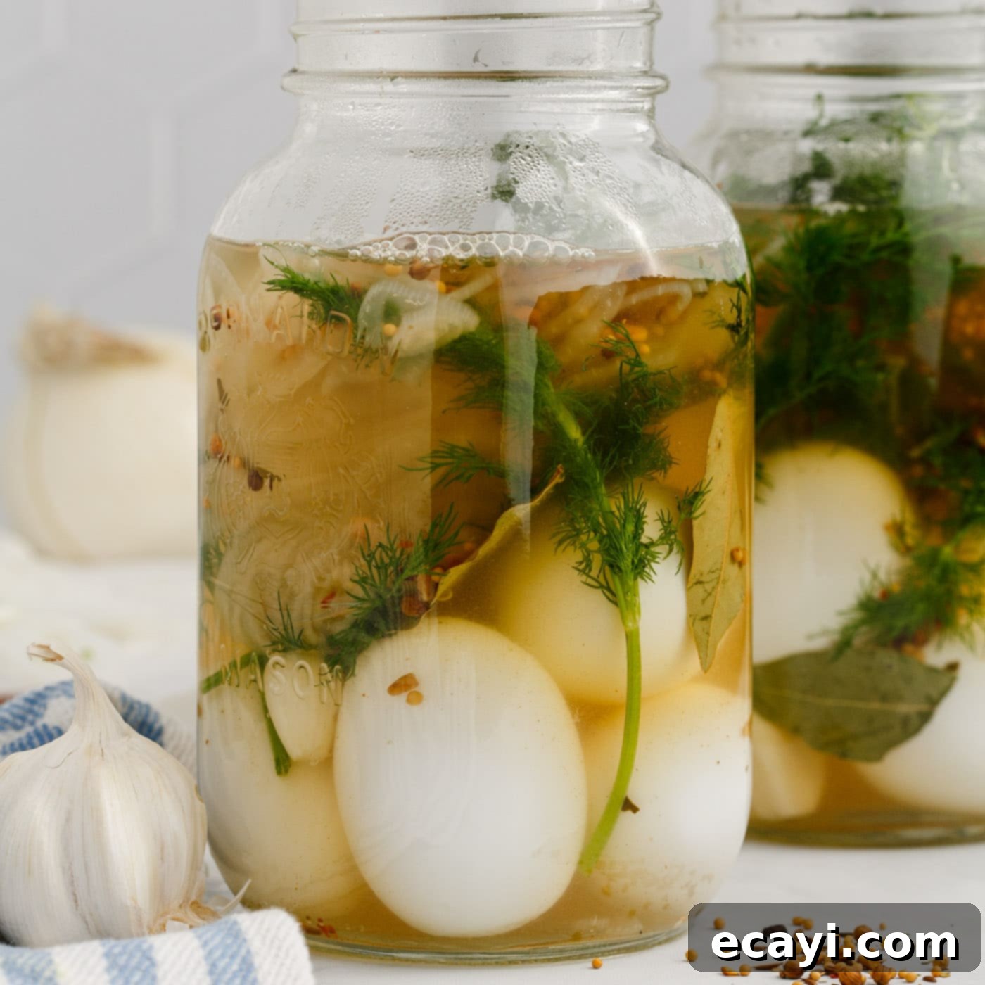 Perfectly Pickled Eggs 9 Hot brine being carefully poured over the eggs and herbs in a mason jar.