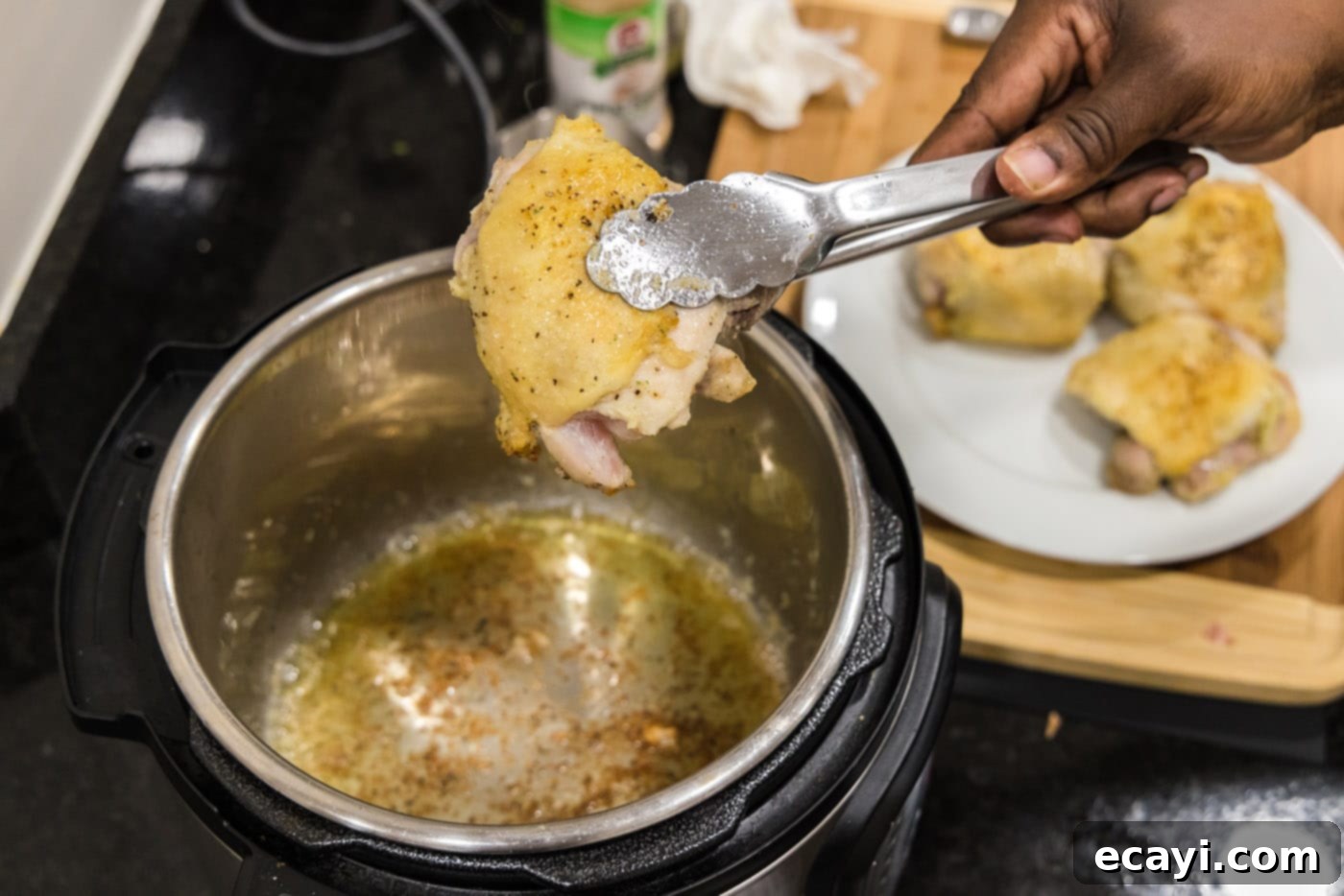 Effortless Instant Pot Chicken Thighs 8 seared chicken on tongs over instant pot