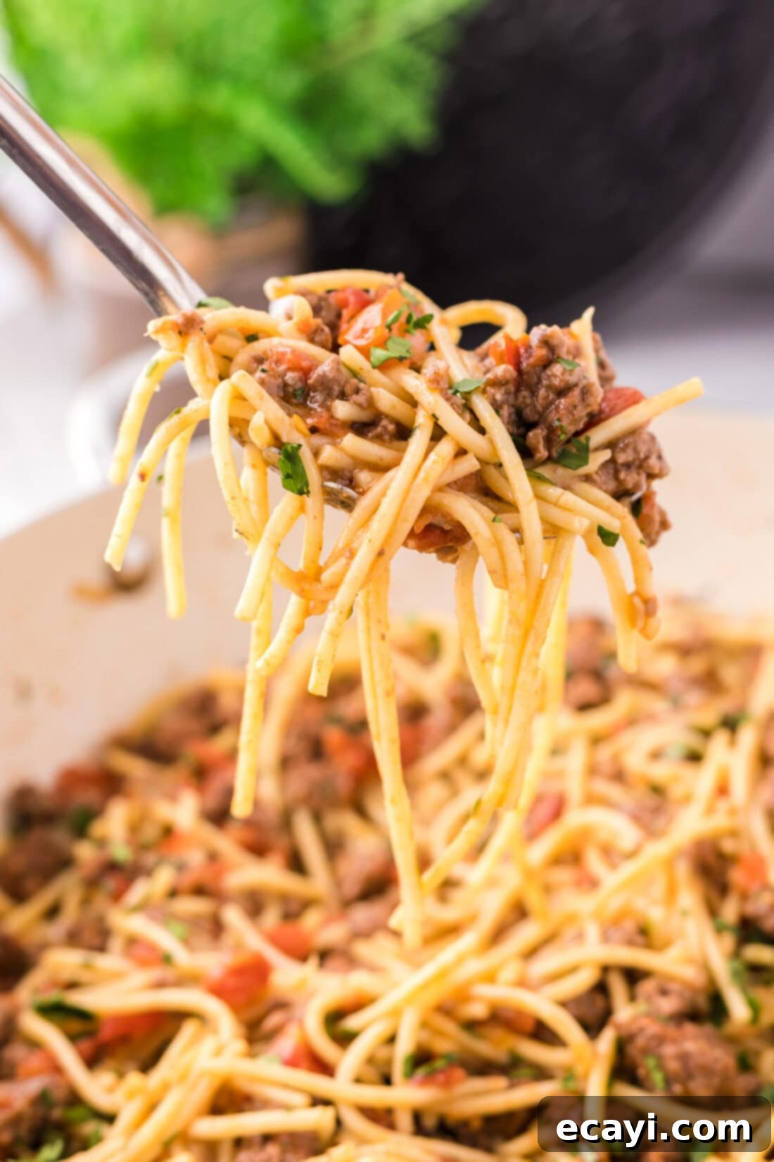 Tex-Mex Spaghetti 3 Spoonful of Taco Spaghetti being lifted out of the skillet of Taco Spaghetti