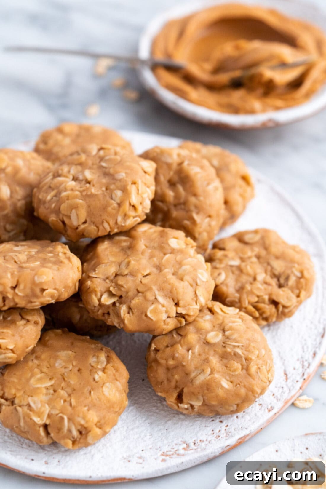 Peanut Butter Bliss Bites 2 Freshly made No Bake Peanut Butter Cookies on a plate, with a jar of peanut butter in the background
