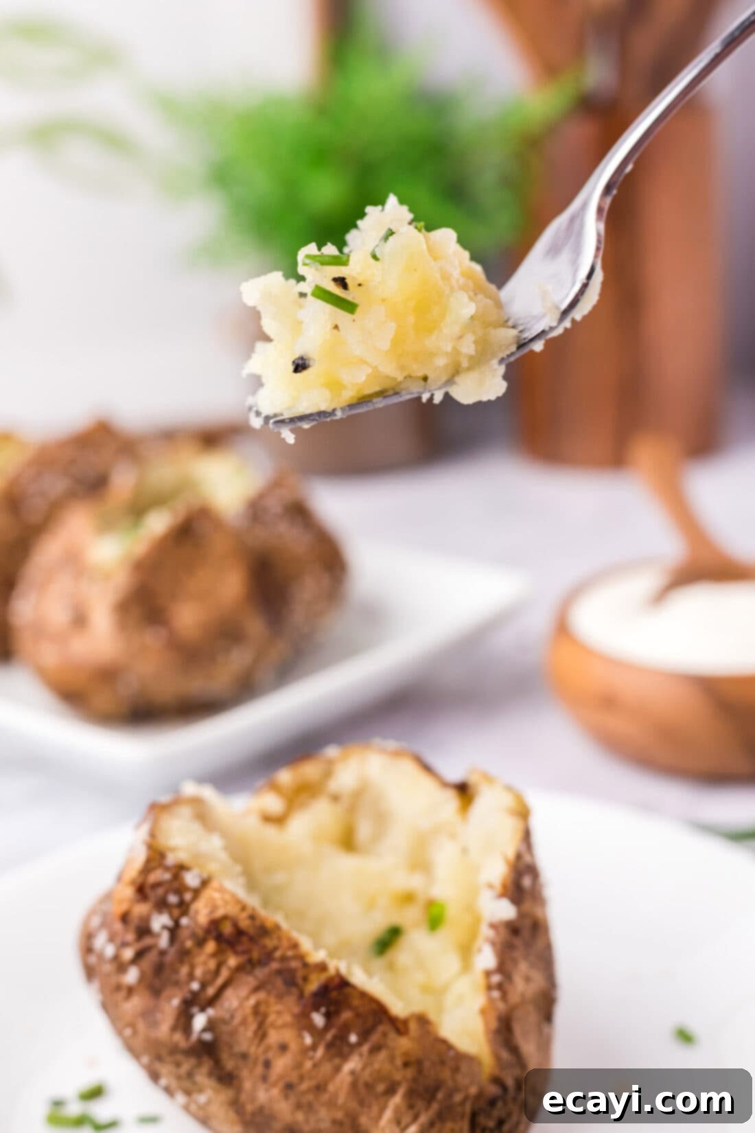 Baked Potato Perfection 2 Piece of Baked Potato on a fork held above a spilt open Baked Potato